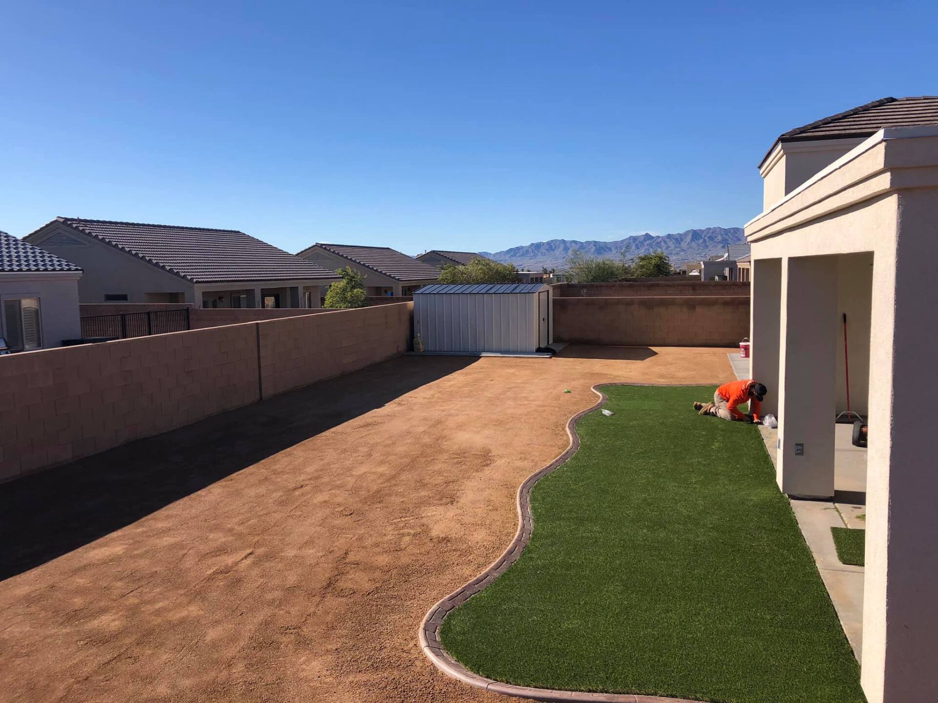 A man is working on a lawn in front of a house.