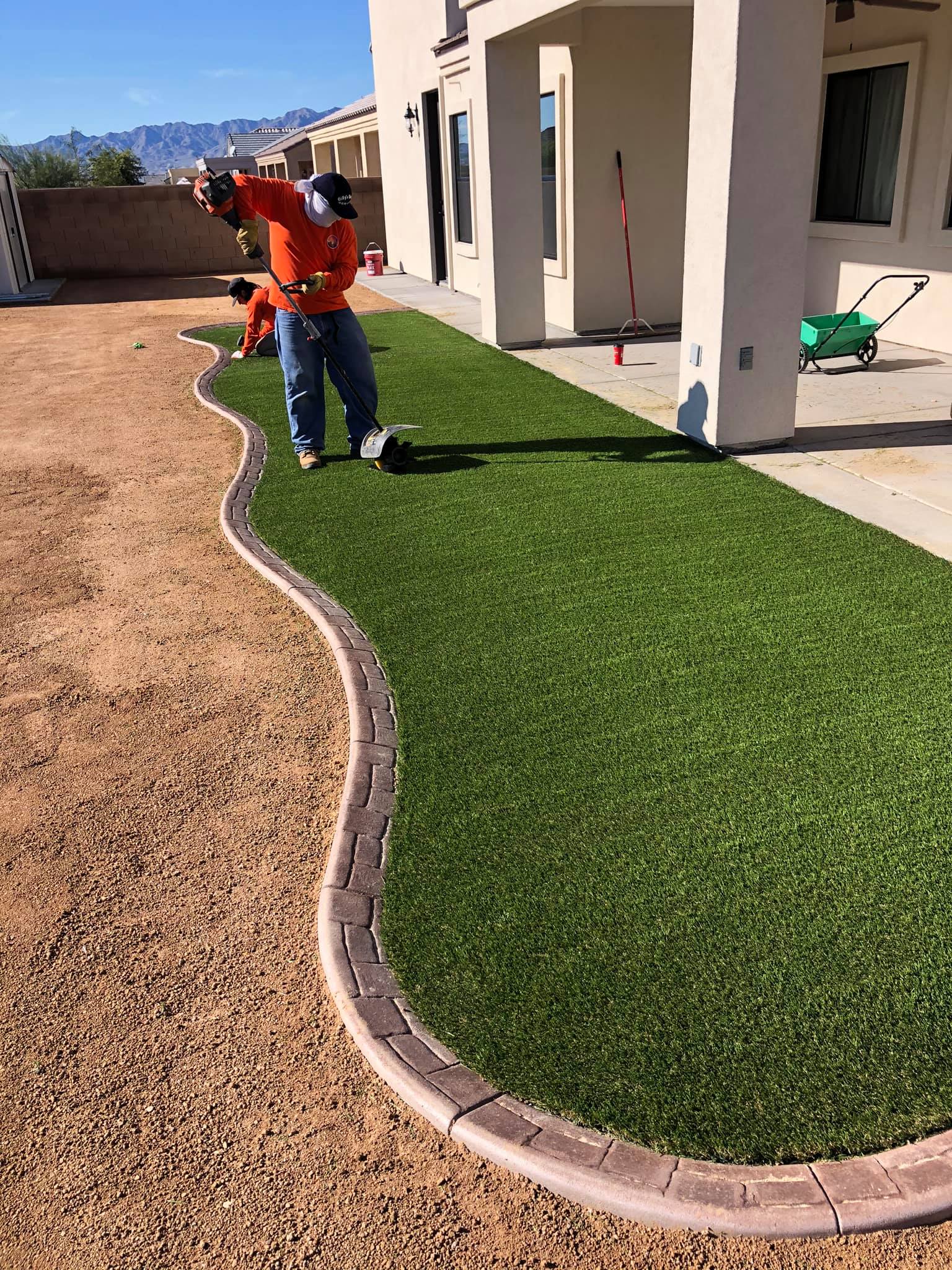 A man is working on a lawn in front of a house.