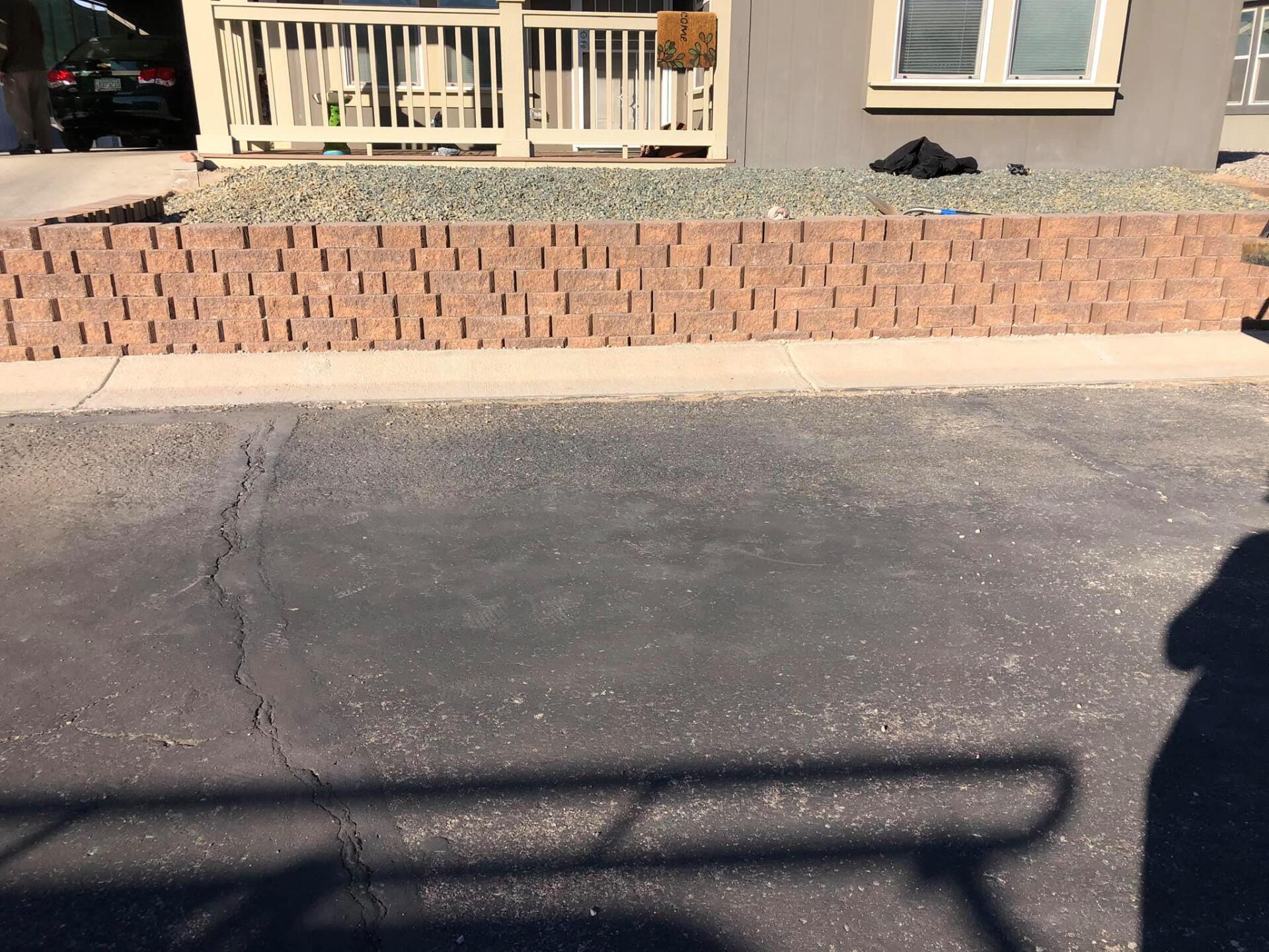 A brick wall in front of a house with a white railing