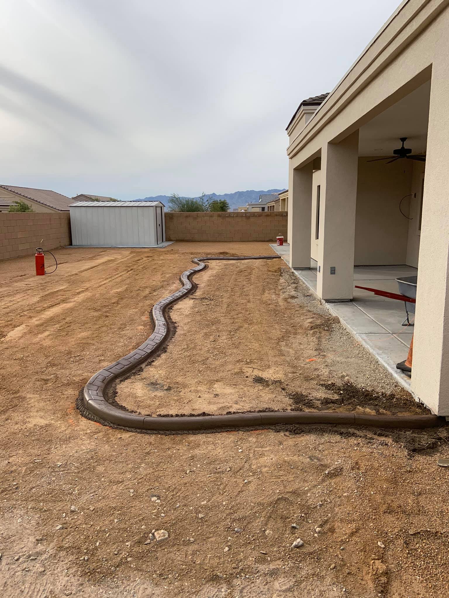 A large snake is laying in the dirt in front of a house.