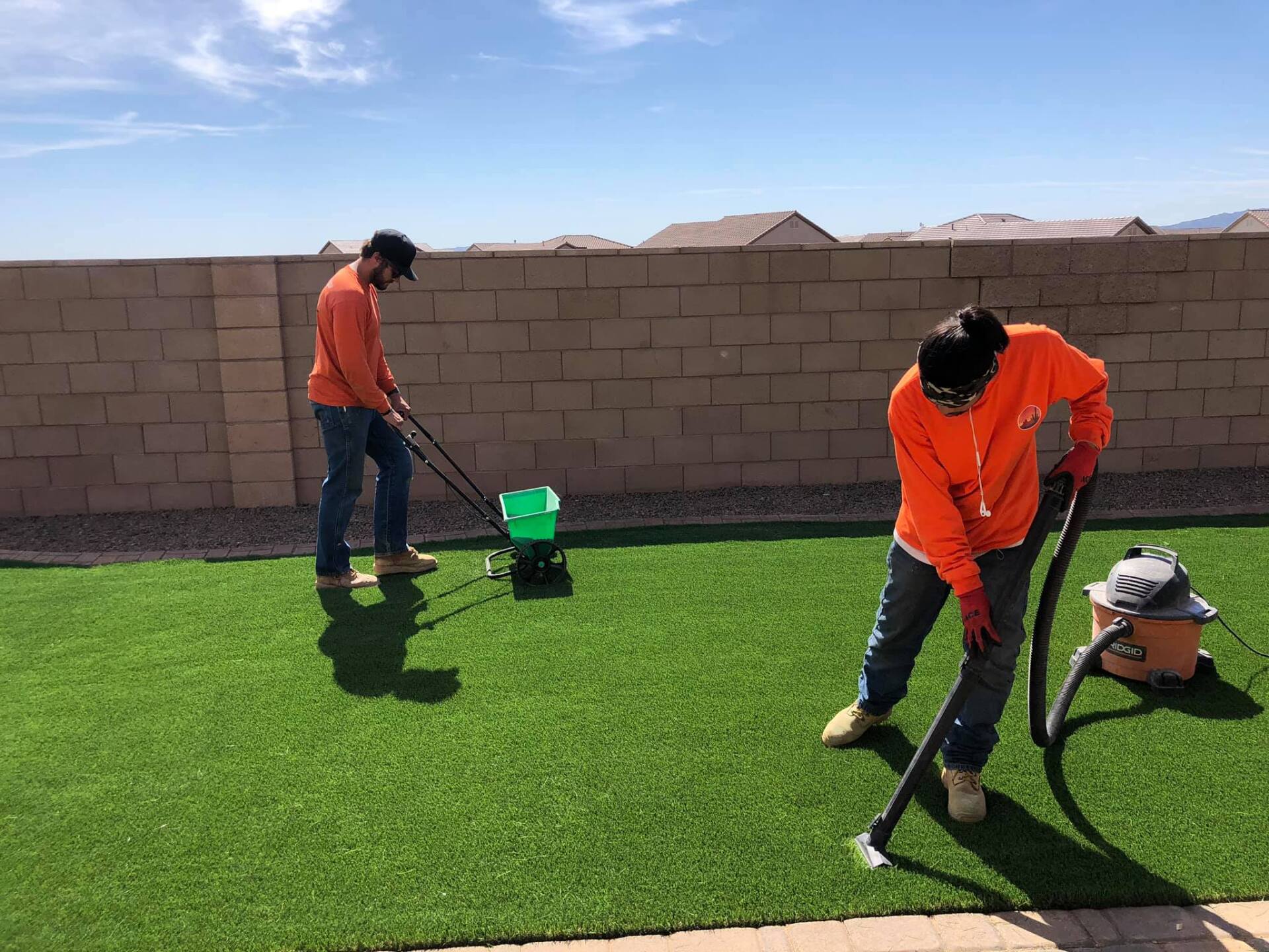 Two men are cleaning a lawn with a vacuum cleaner.