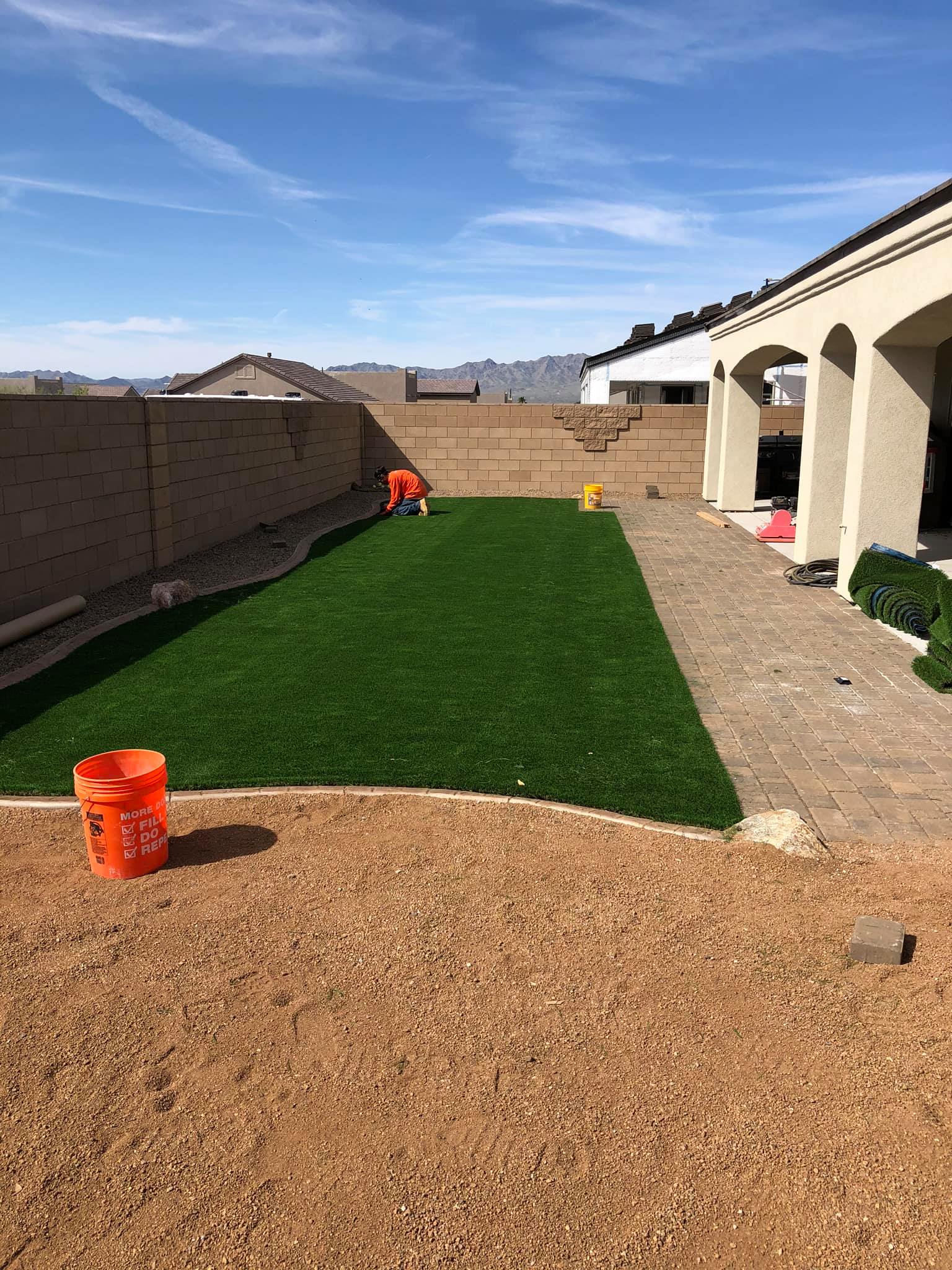 A backyard with a lawn and a bucket in the middle of it.