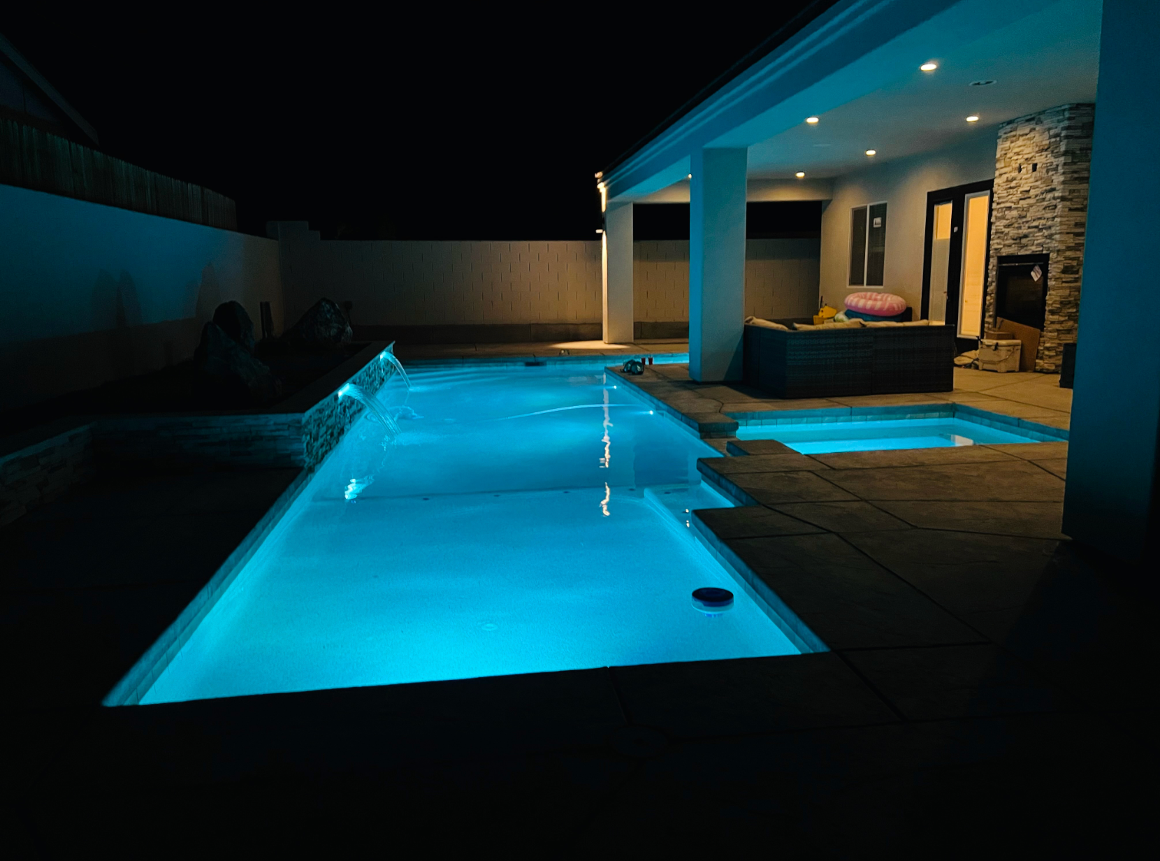 A large swimming pool is lit up at night.