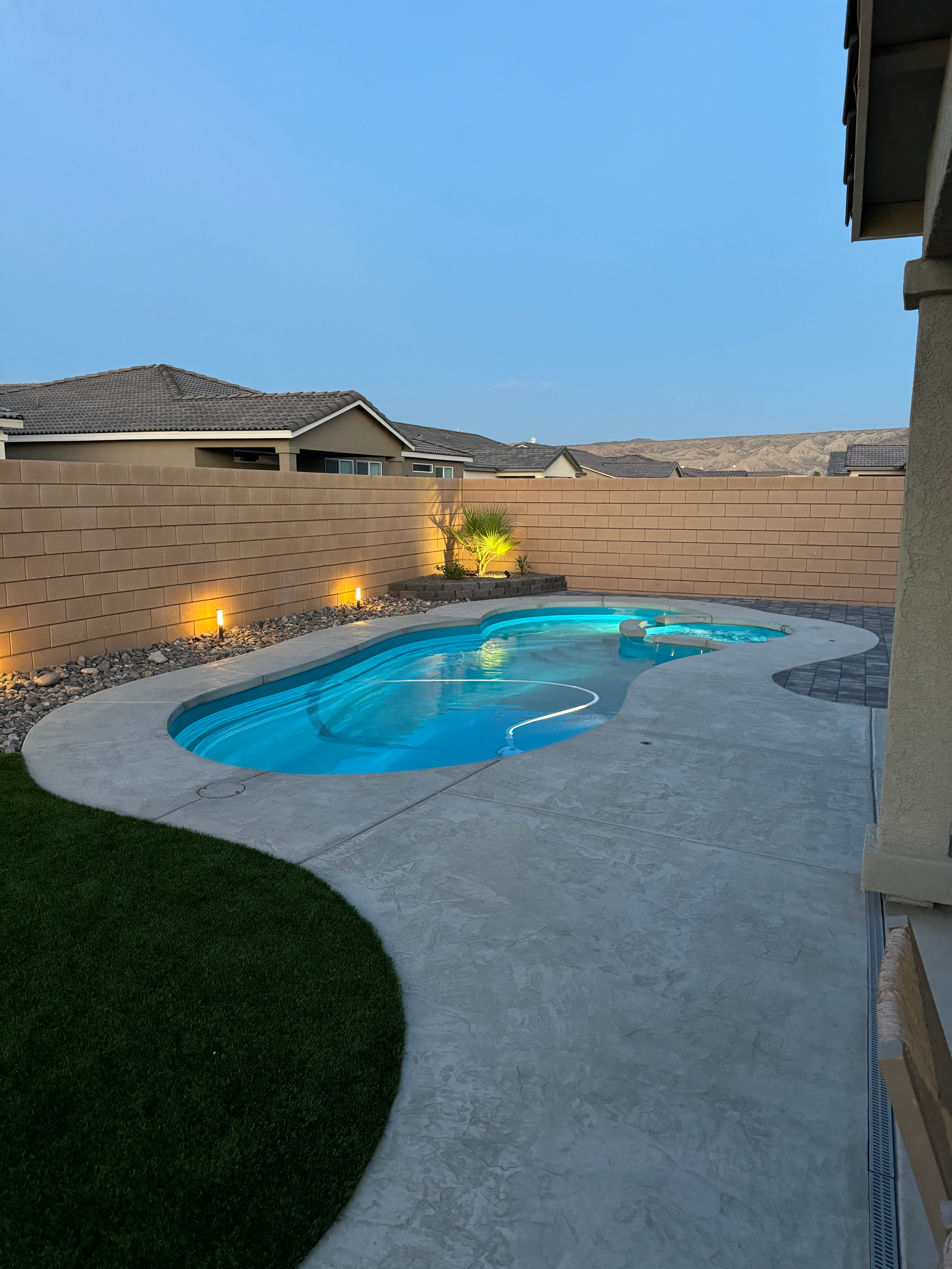 A large swimming pool is in the backyard of a house.