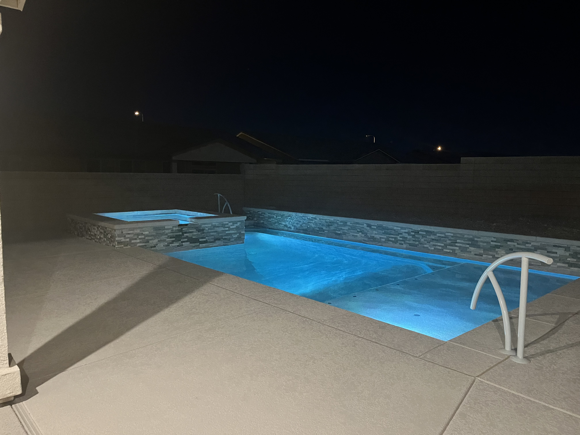 A large swimming pool is lit up at night.