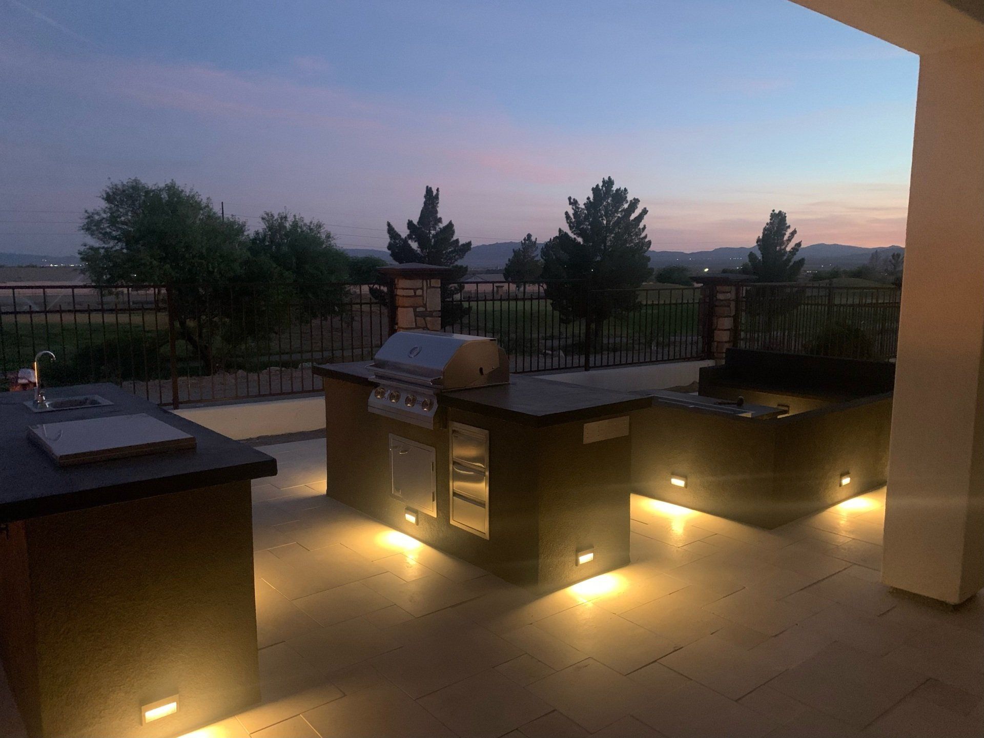 A patio with a grill and a sink at night.