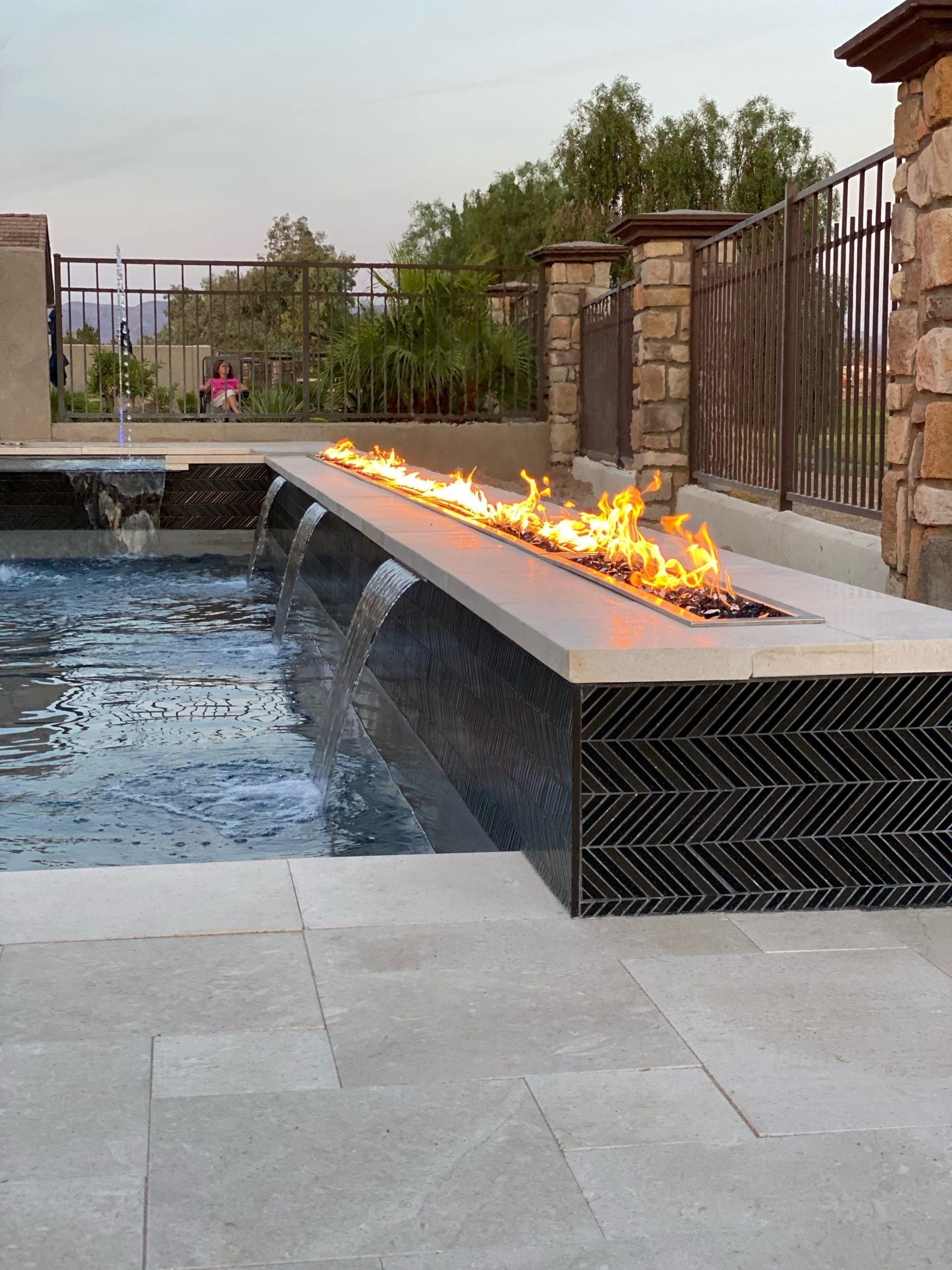 A swimming pool with a fire pit in the middle of it