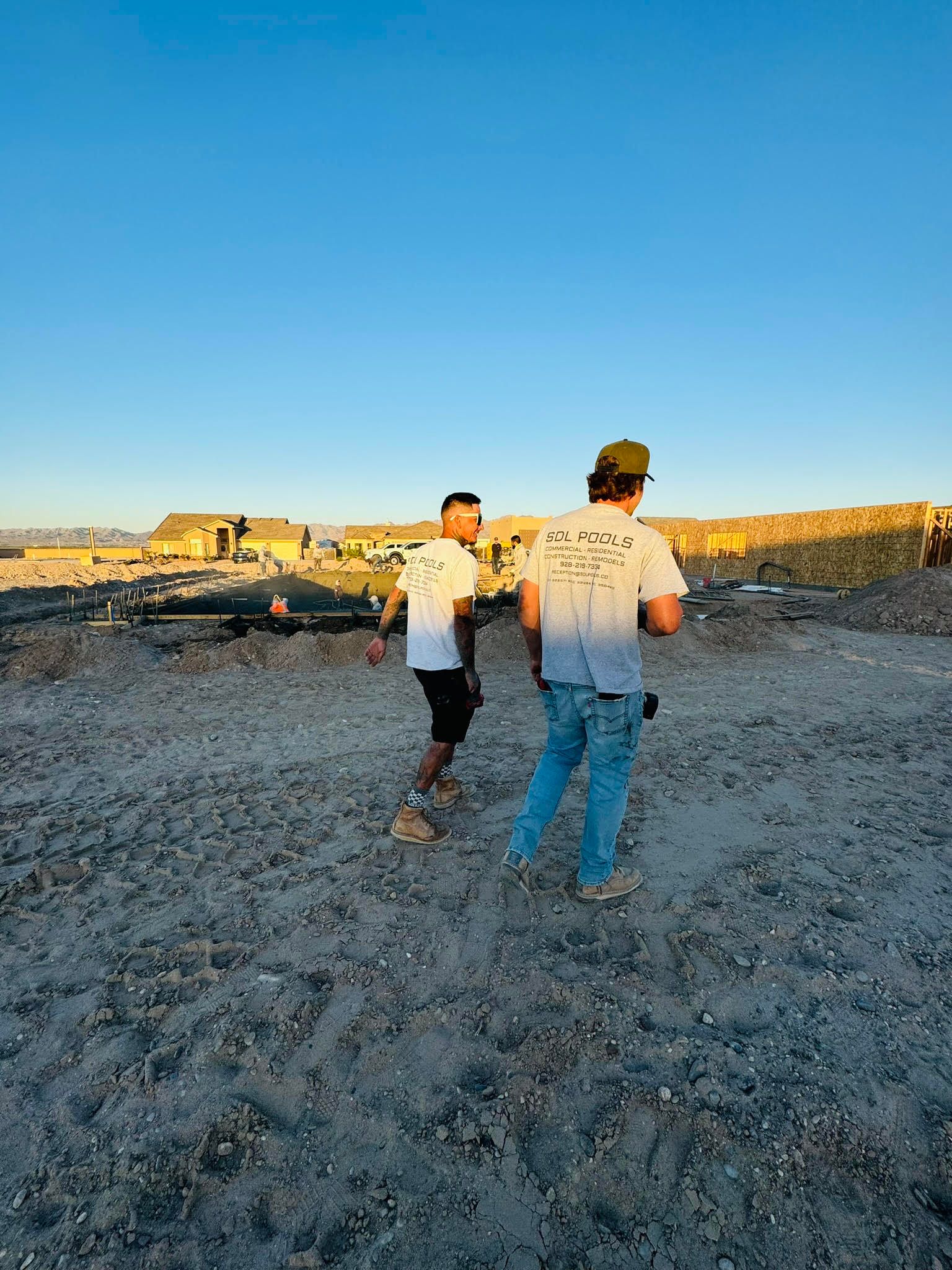 Two men are standing on top of a dirt field.