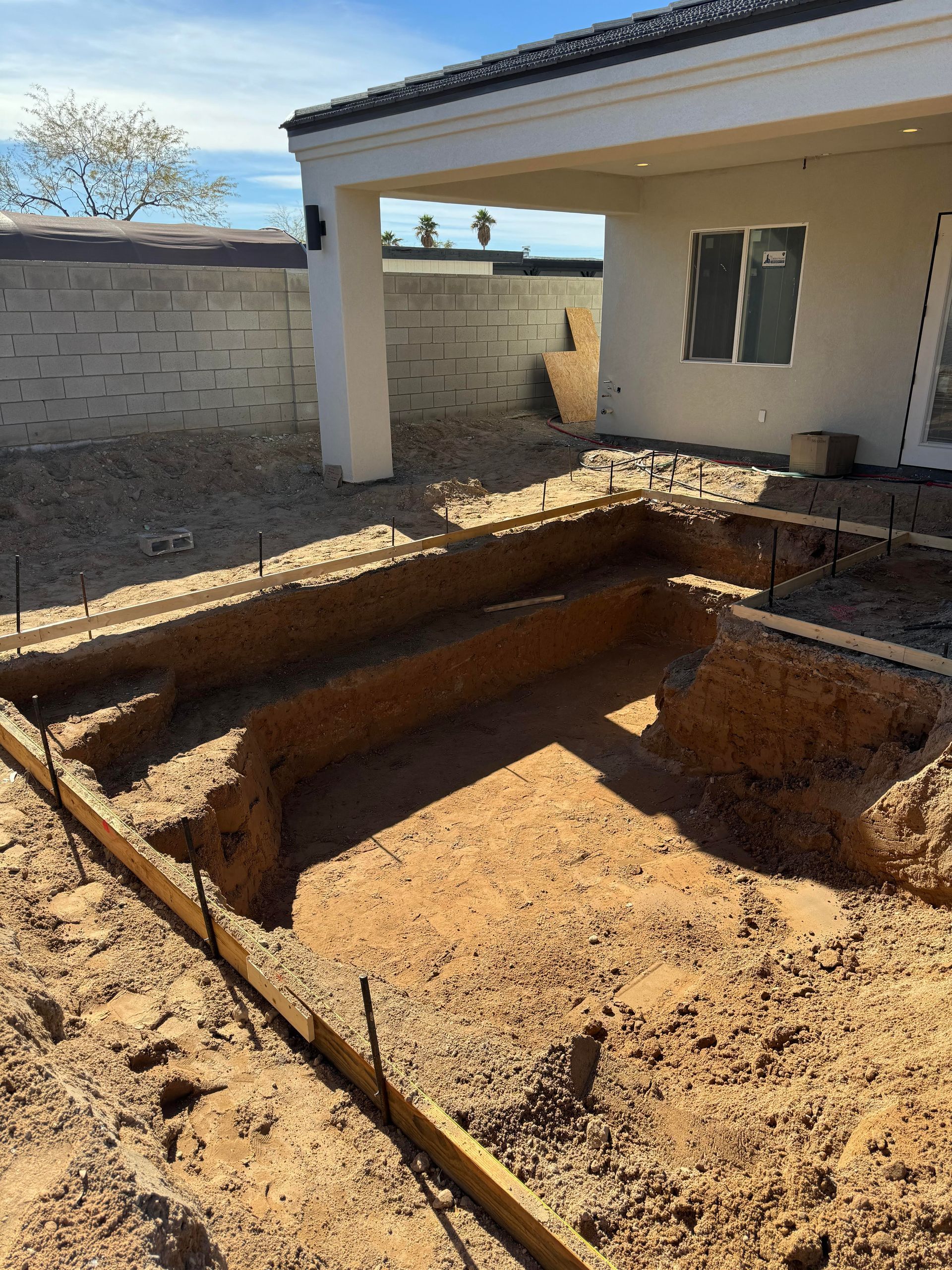 A pool is being built in the backyard of a house