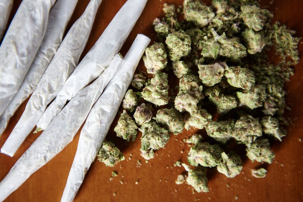Cannabis buds and pre-rolled joints arranged on a wooden surface.