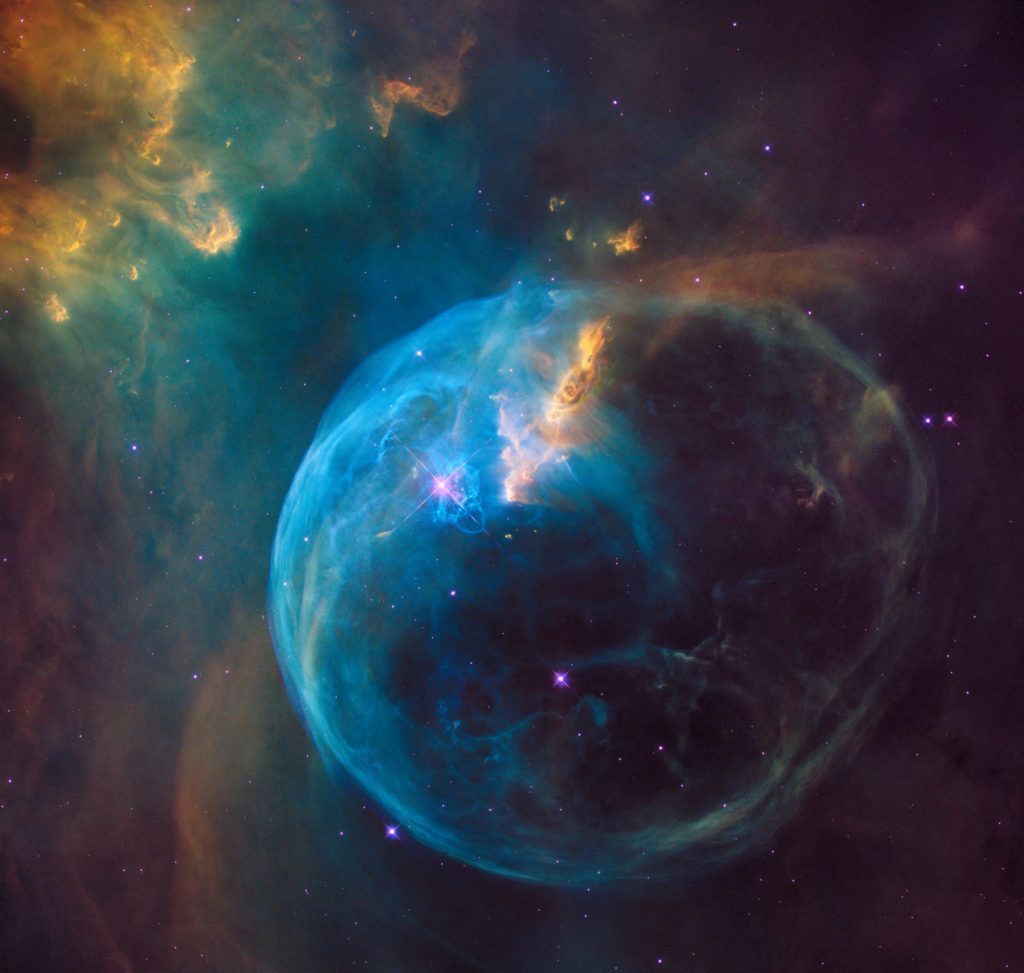 A vibrant, blue and orange nebula, resembling a cosmic bubble, with stars and colorful gas clouds throughout.