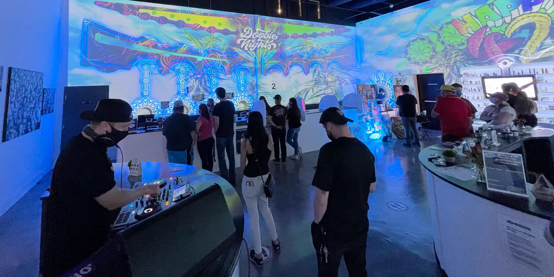 The store floor at Doobie Nights on 4/20 full of people, with a DJ on the left side and Happy 420 on the walls.