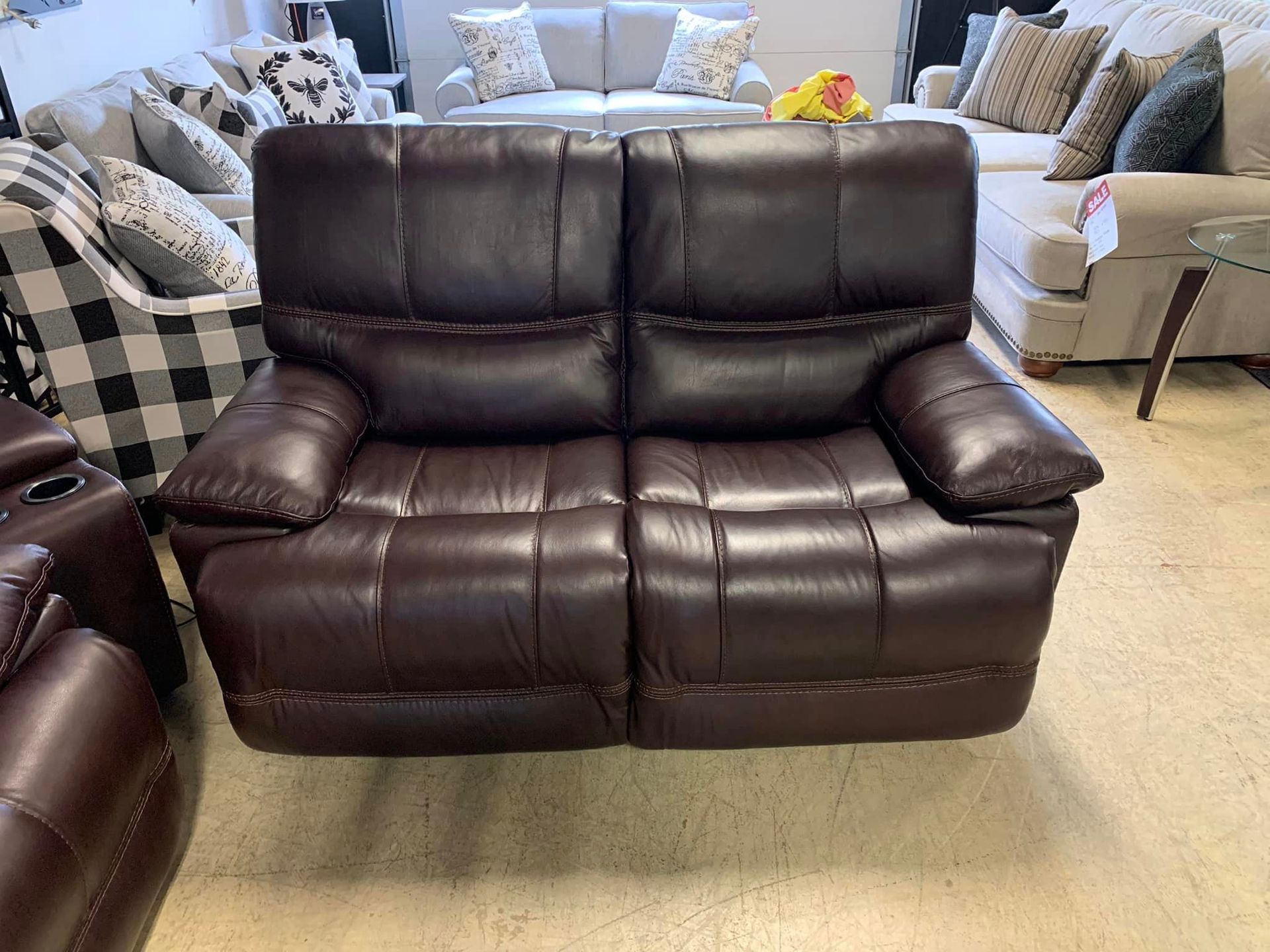 A brown leather recliner couch is sitting in a living room next to a couch.