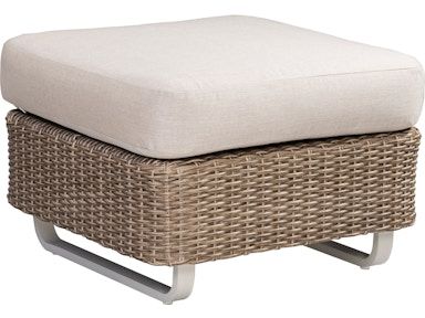 A wicker ottoman with a white cushion on top