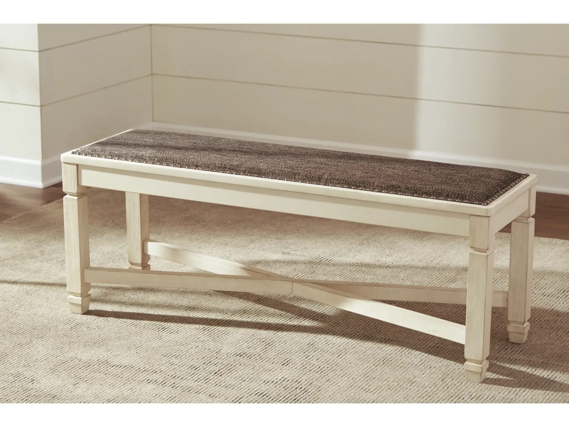 A white bench with a brown cushion is sitting on a carpet in a room.