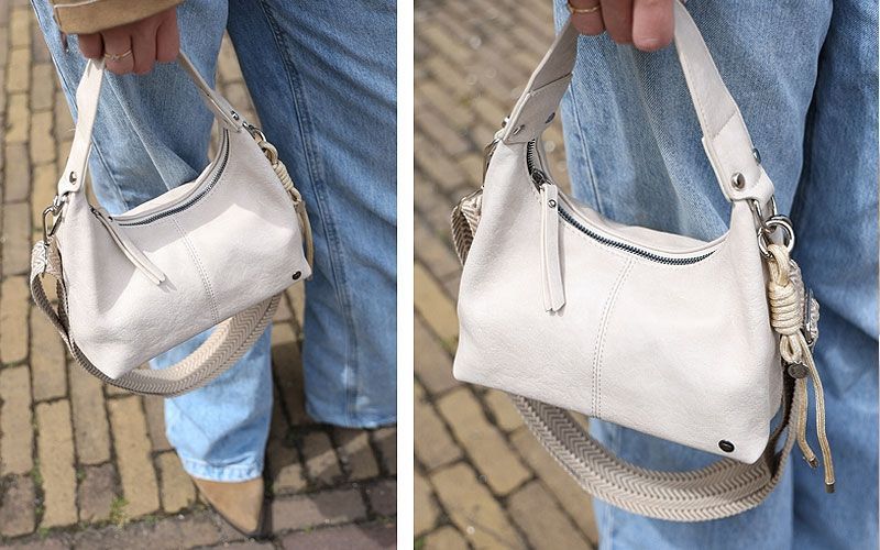 Een vrouw draagt een bruine tas op een geplaveide straat.