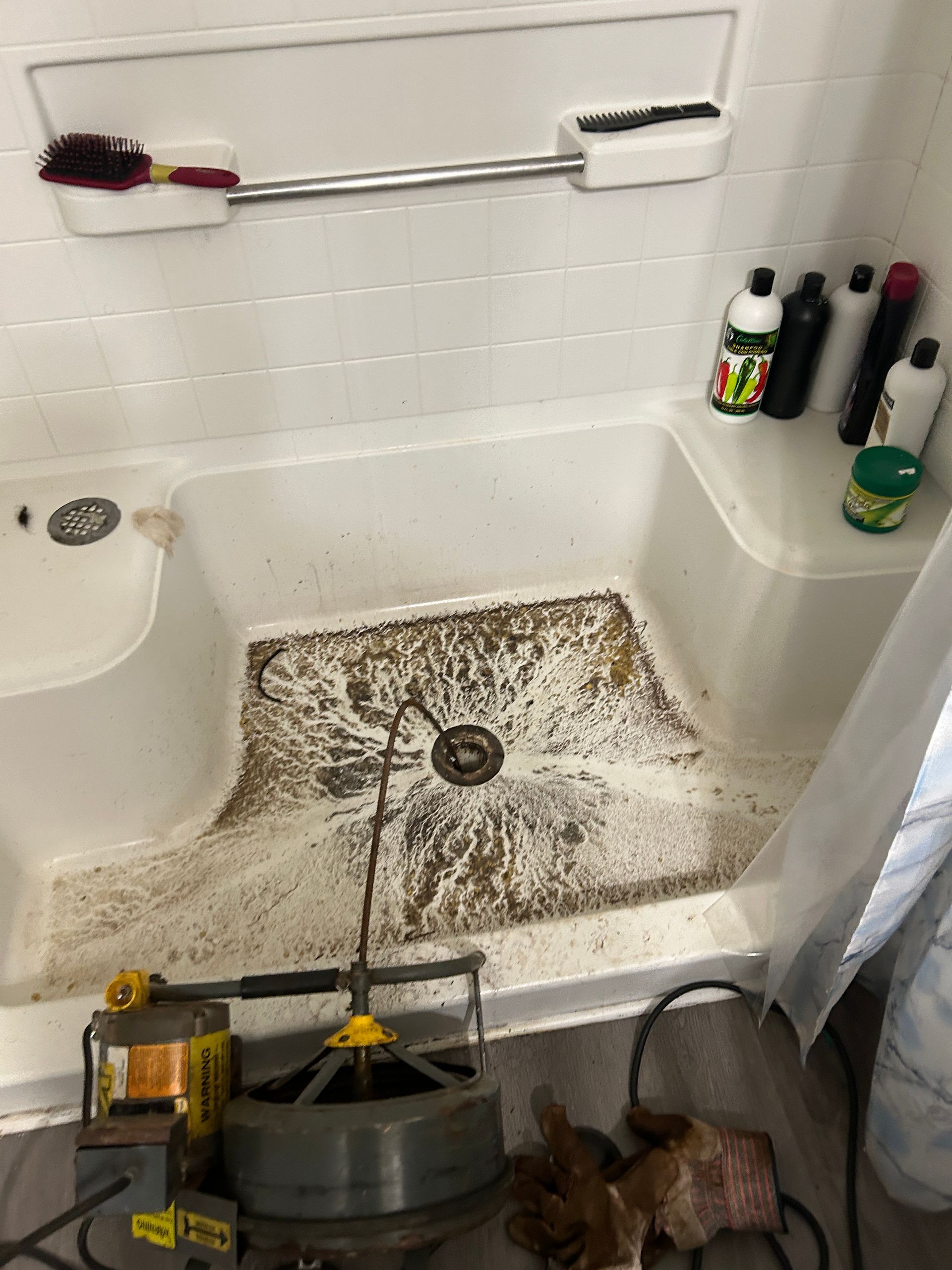 A bathroom with a shower stall and a drain cleaning machine.