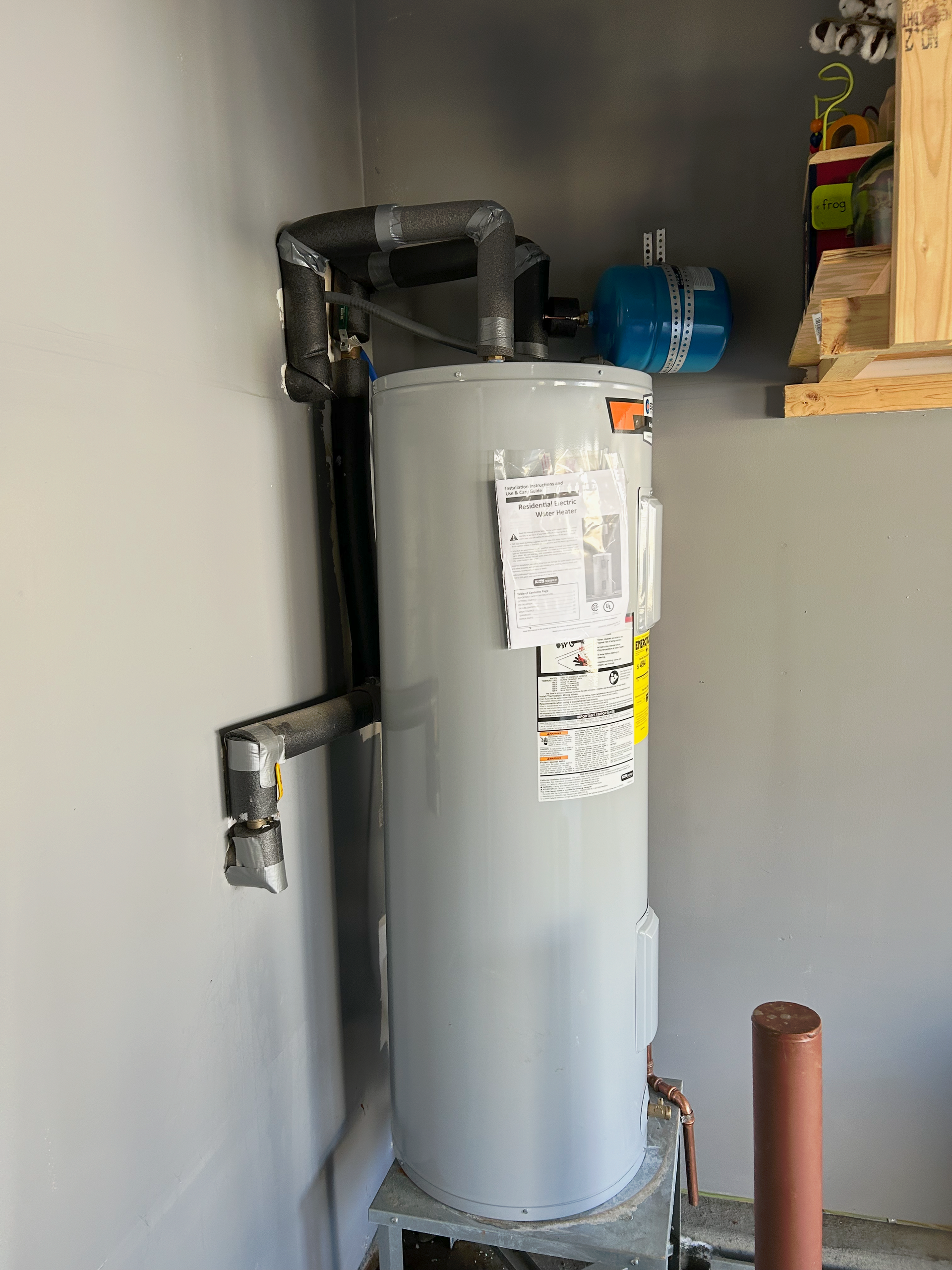 A water heater is sitting in a room next to a wall.