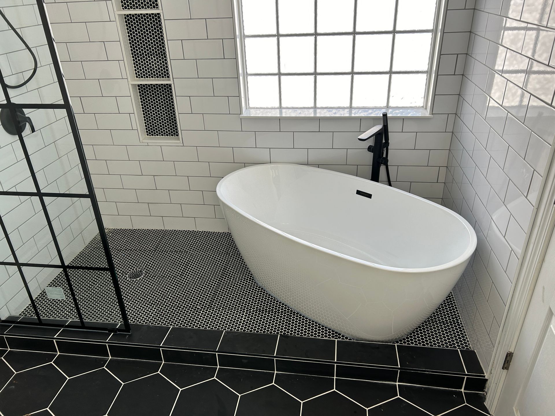 A bathtub is sitting in a bathroom next to a window.