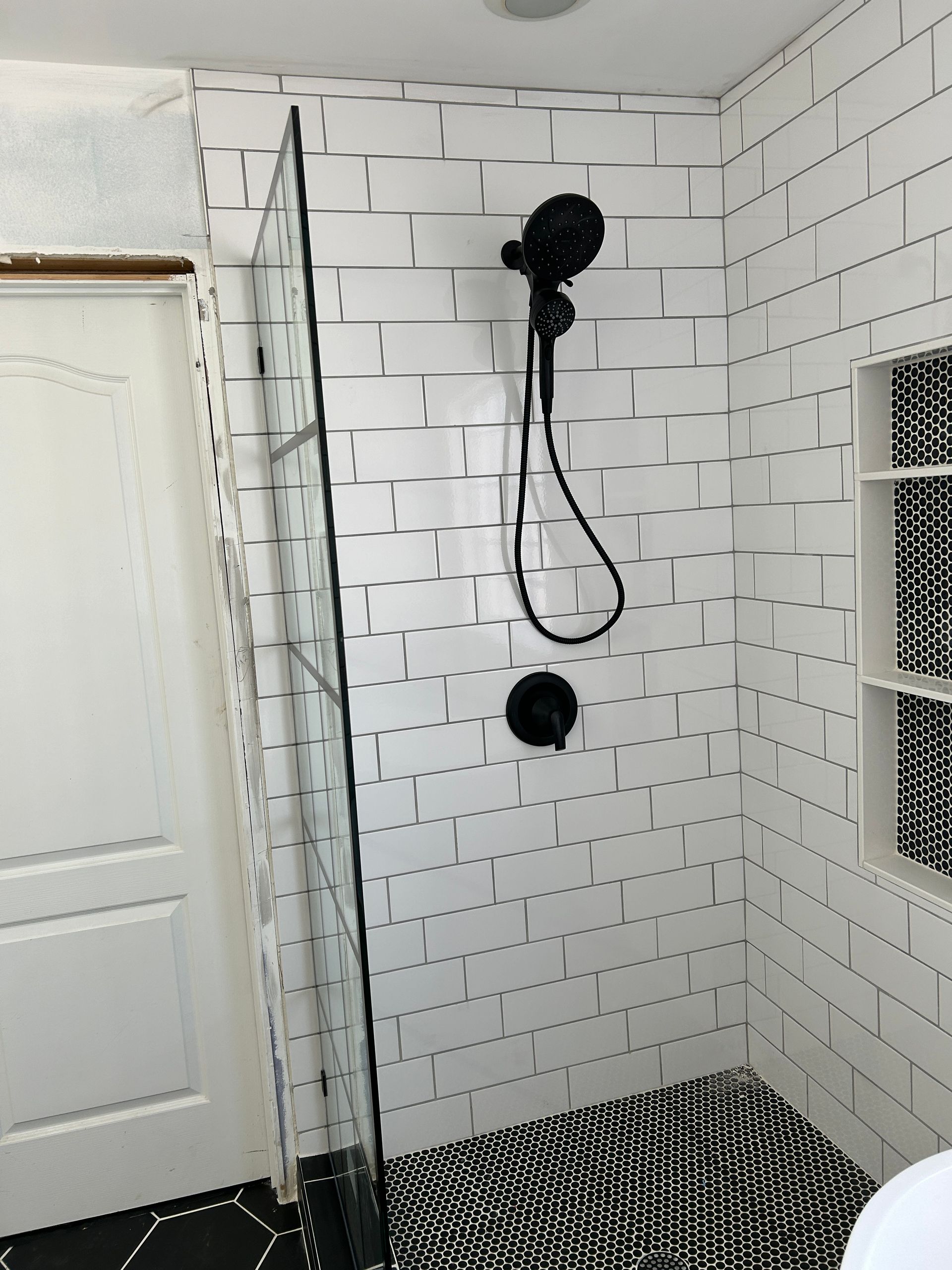 A bathroom with black and white tiles and a walk in shower.