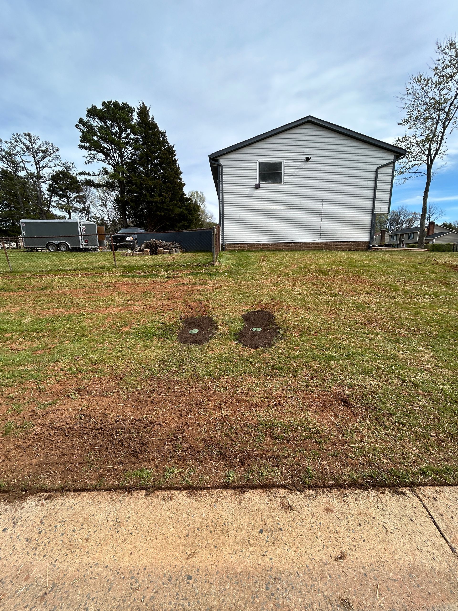 A white house is sitting on top of a lush green field next to a sidewalk.