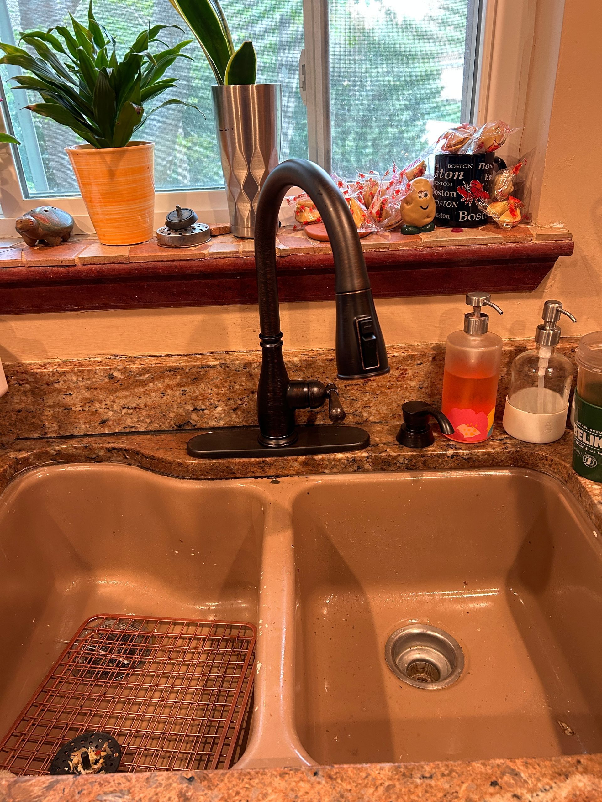 A kitchen sink with a faucet and a soap dispenser on the counter.