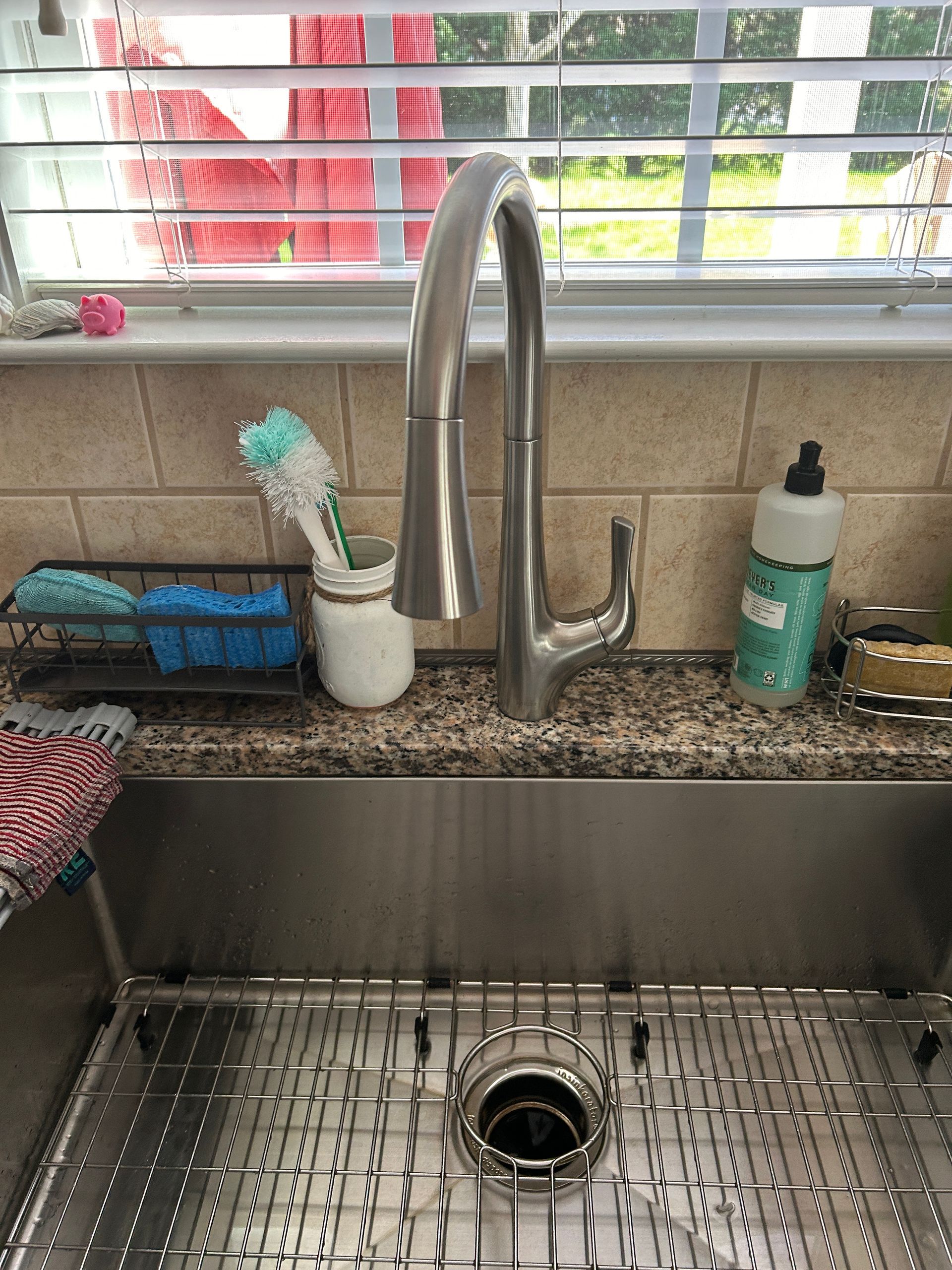 A kitchen sink with a faucet and sponges on the counter.