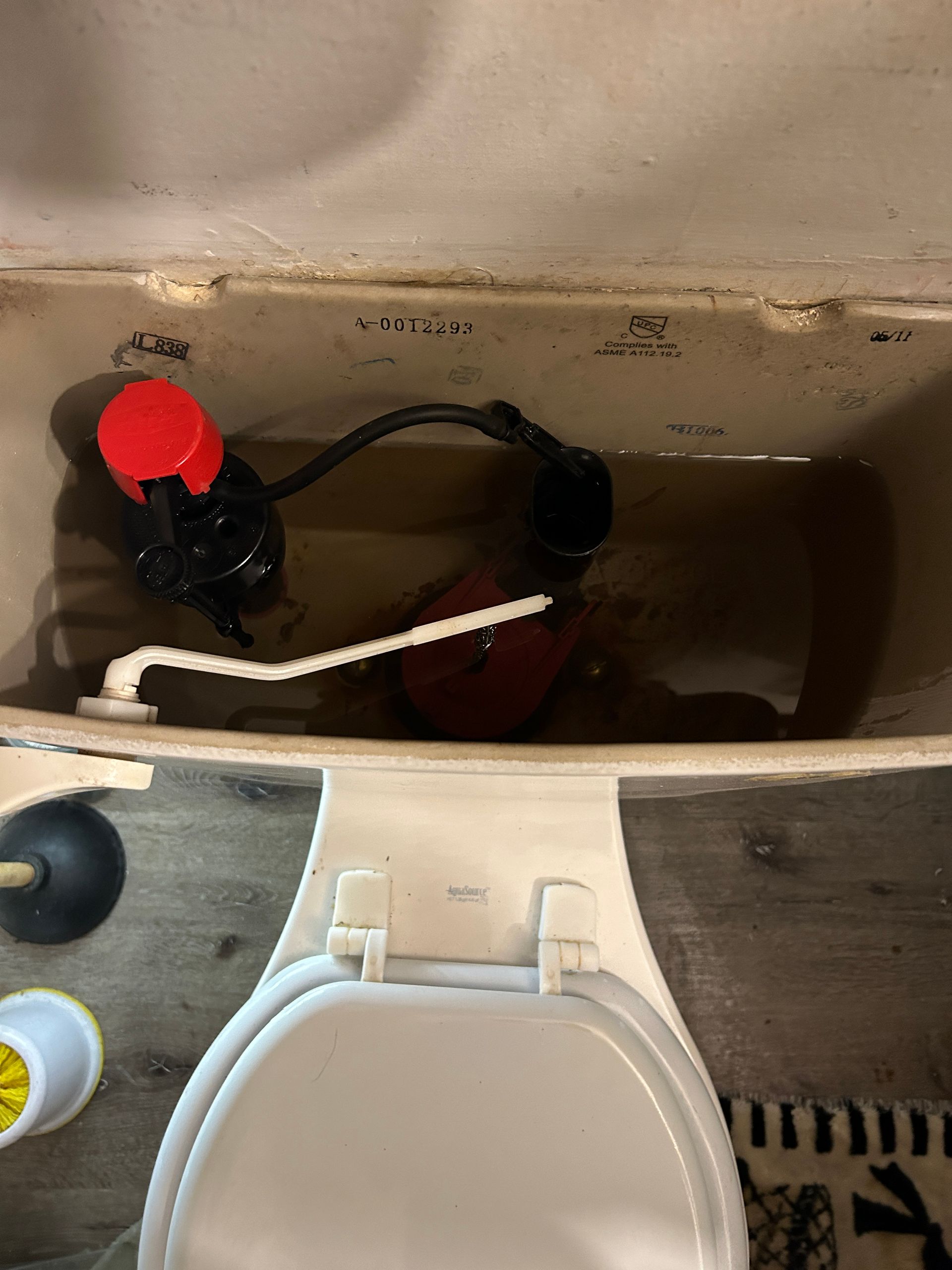 A close up of a toilet with a plunger in it.