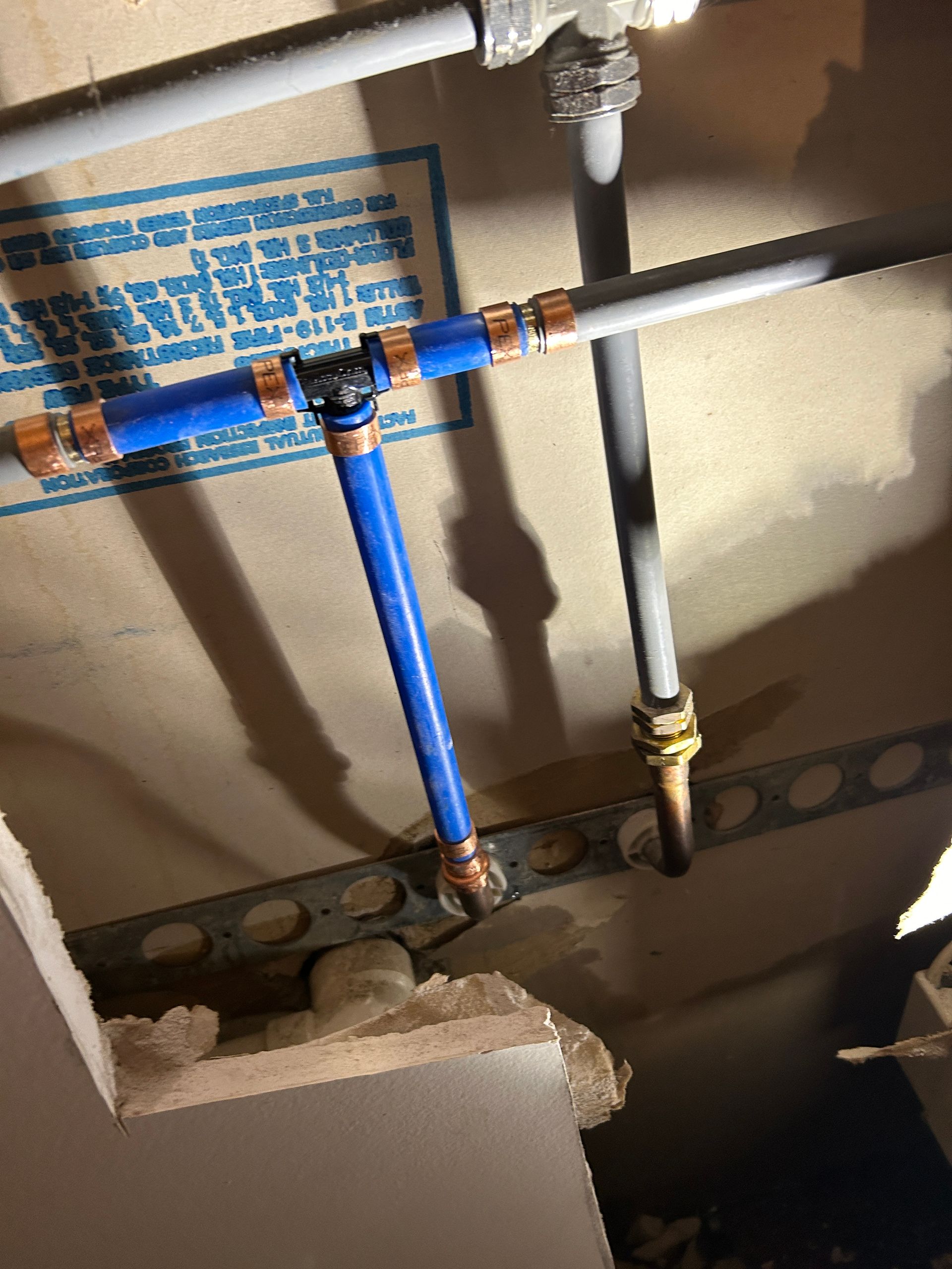 A blue pipe is connected to a white pipe in a room.