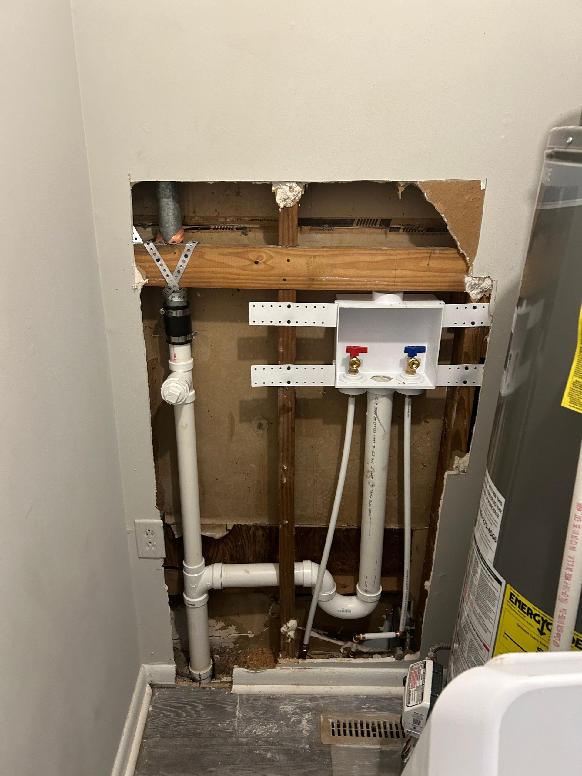 A bathroom with a hole in the wall and pipes coming out of it.