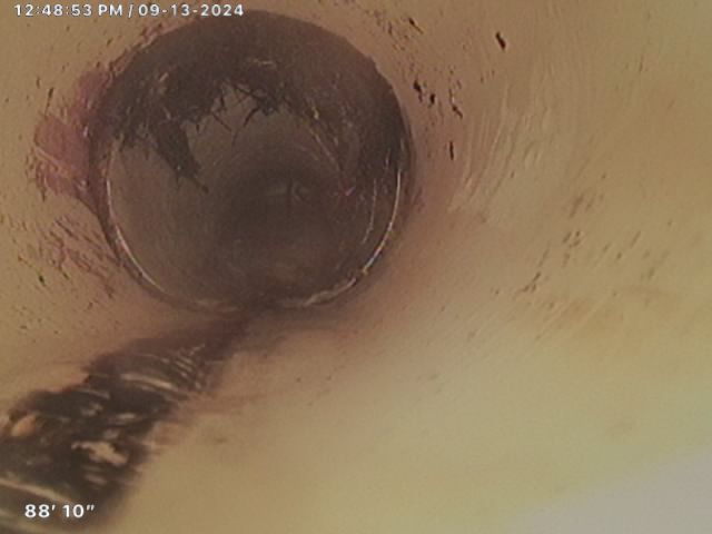 A close up of a drain with a hose coming out of it.