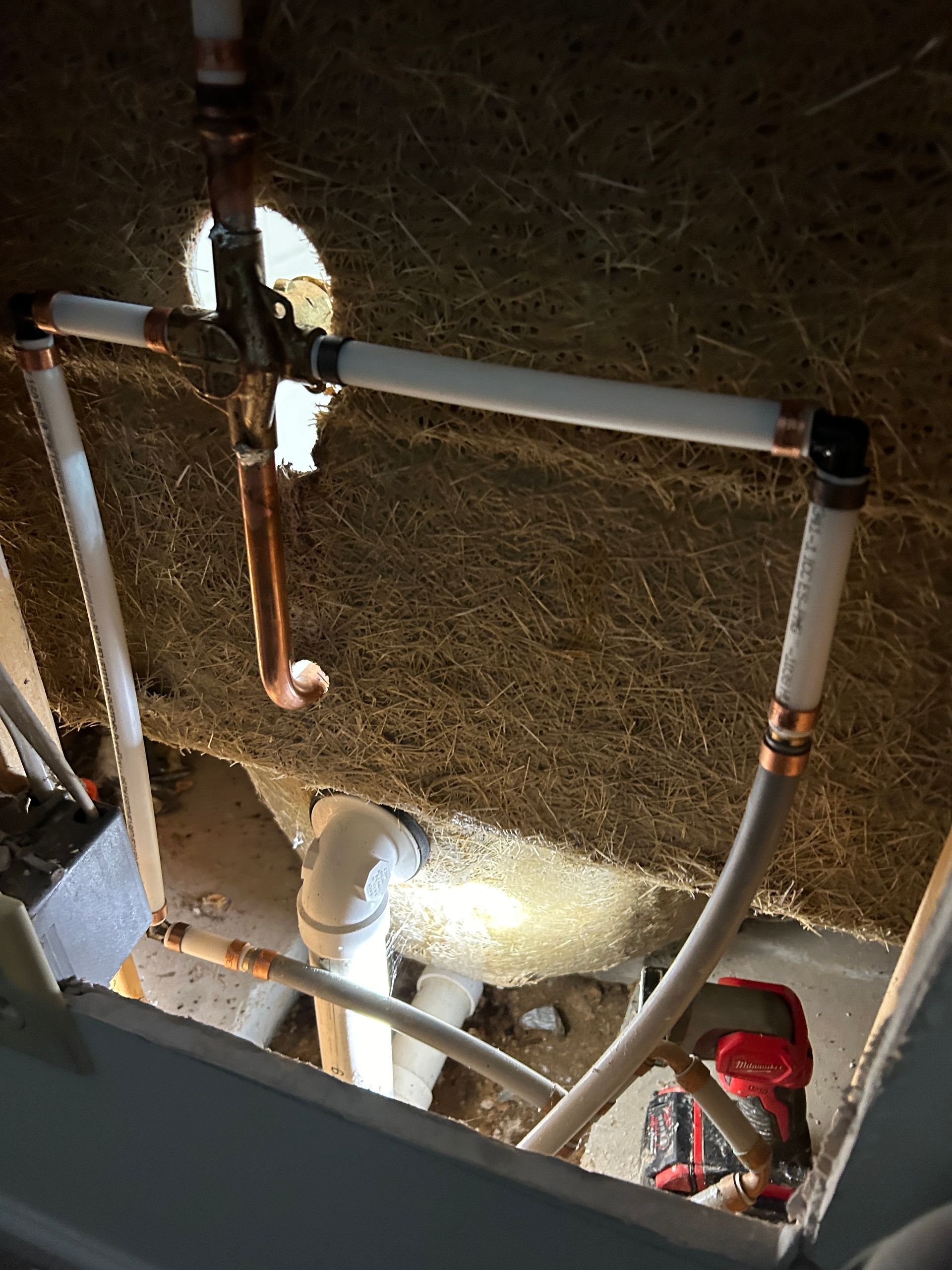 A plumber is working on a pipe in a bathroom.