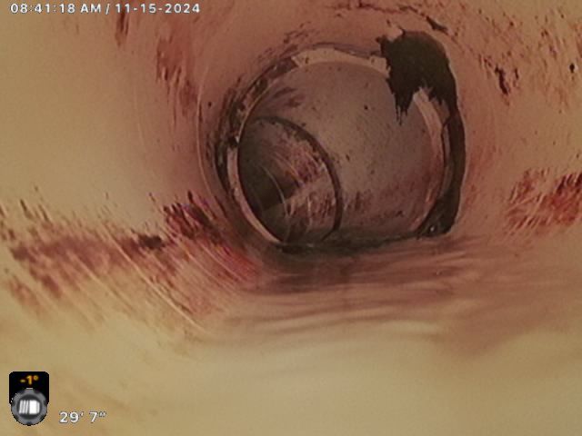 A close up of a drain with a thermometer on it.