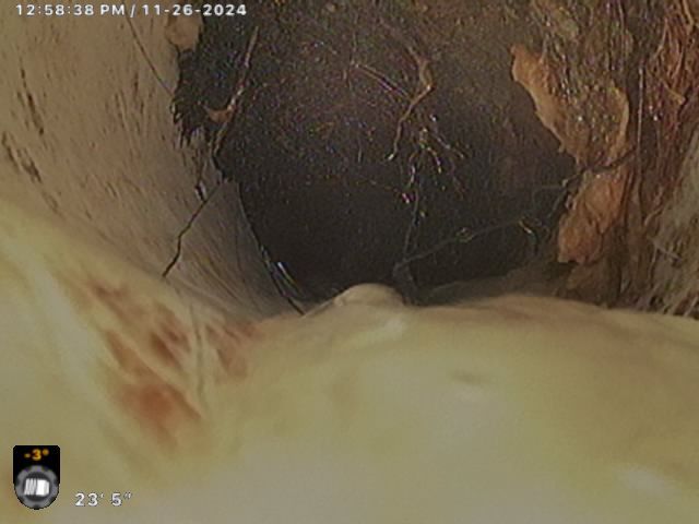 A camera is taking a picture of a hole in a wall.