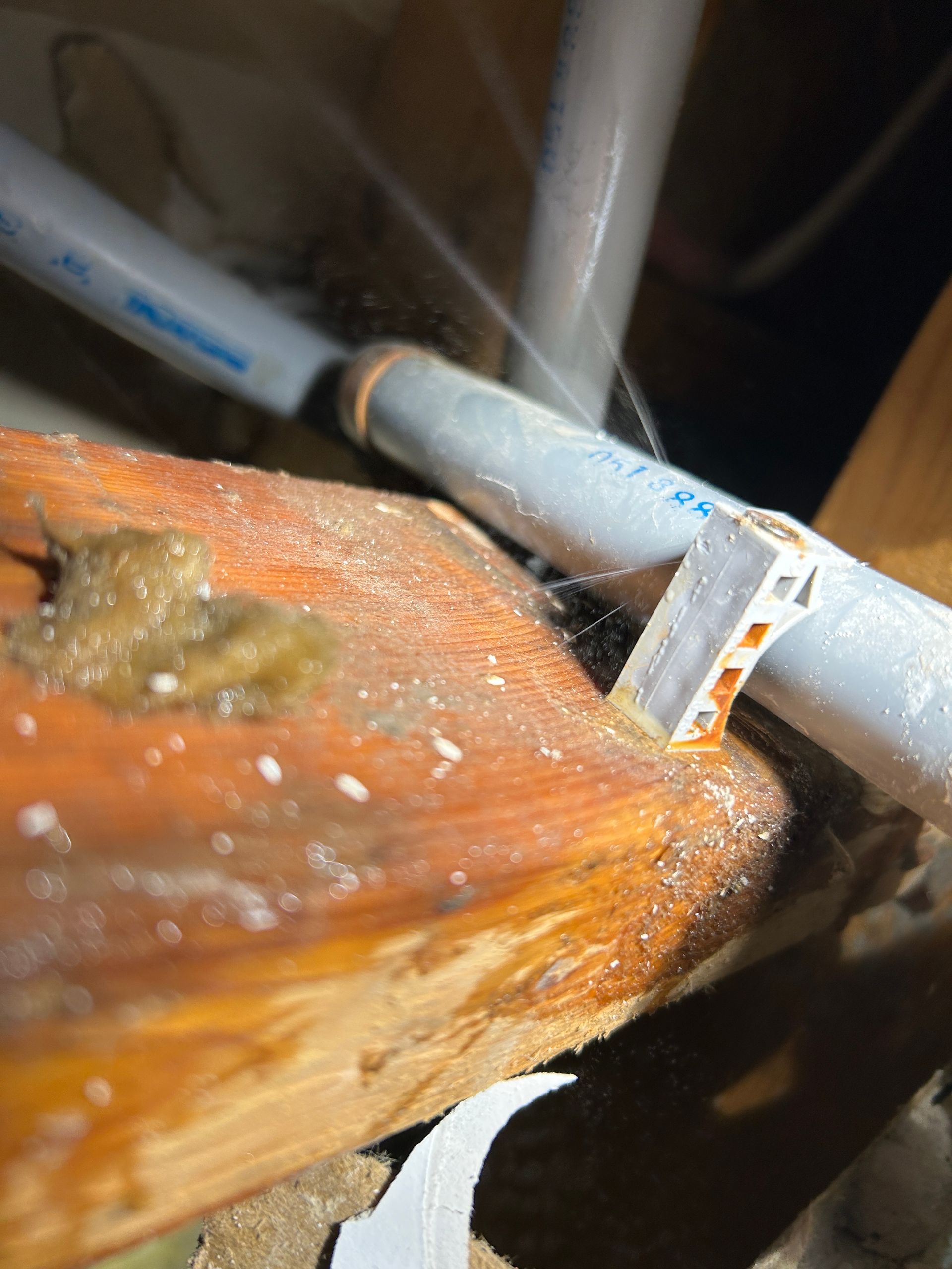 A close up of a piece of wood with a pipe in the background.