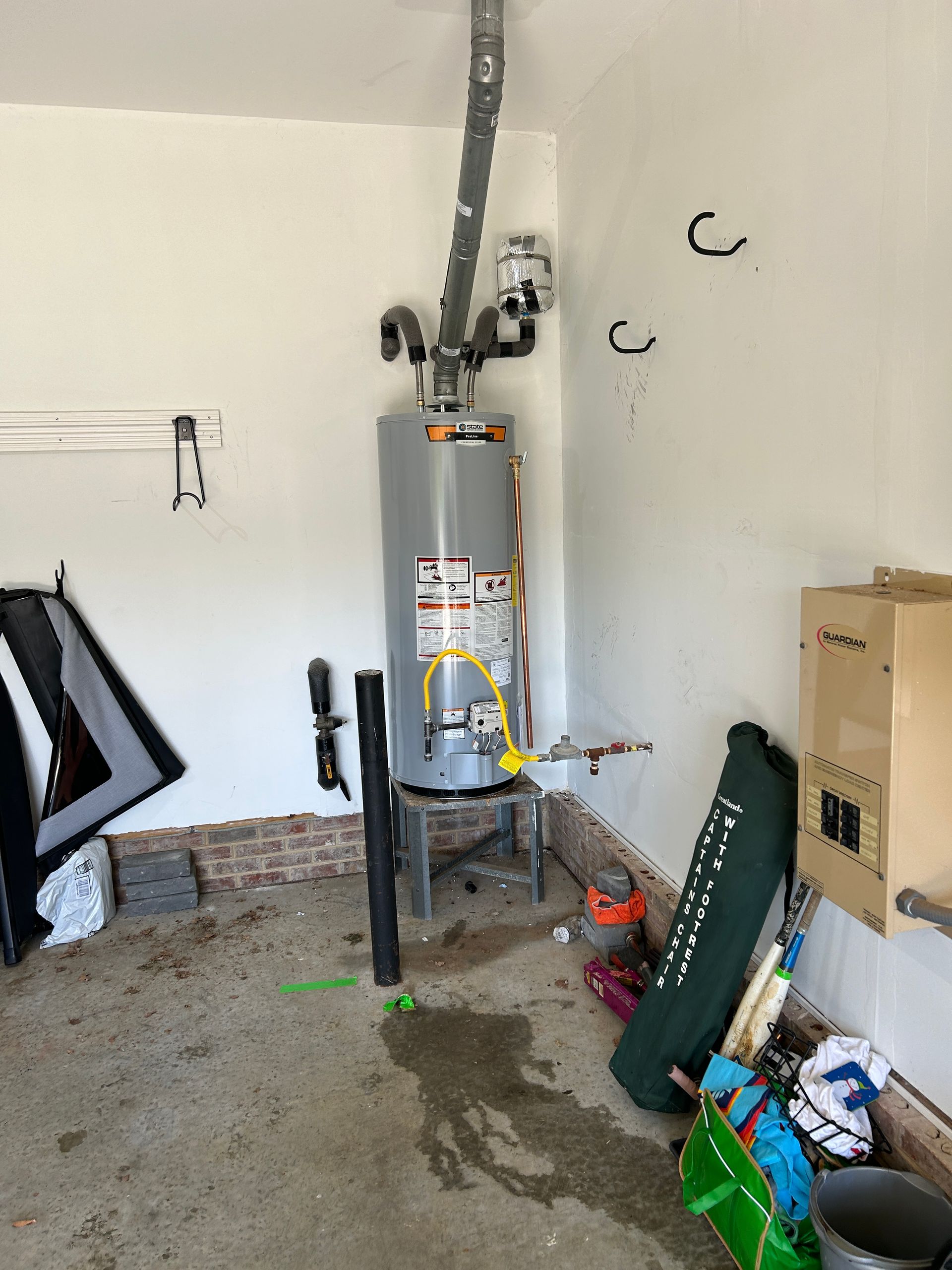 A water heater is sitting in the middle of a garage.