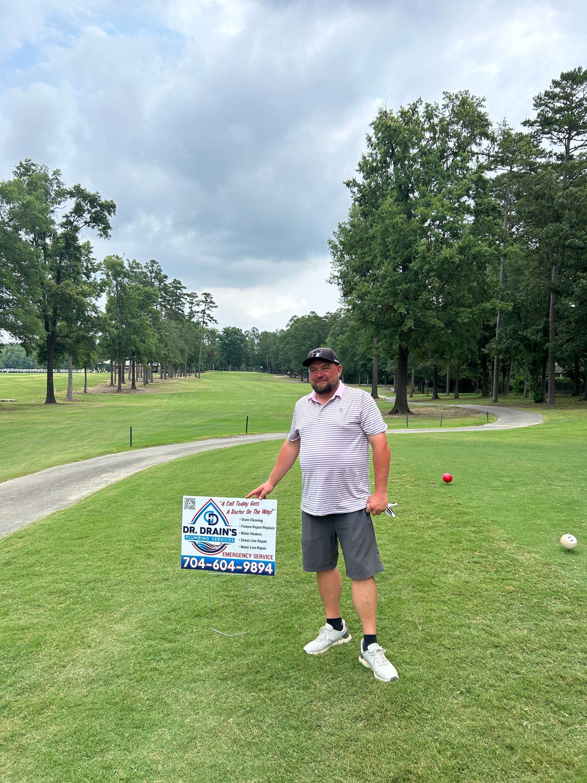 A man is standing on a golf course holding a sign.