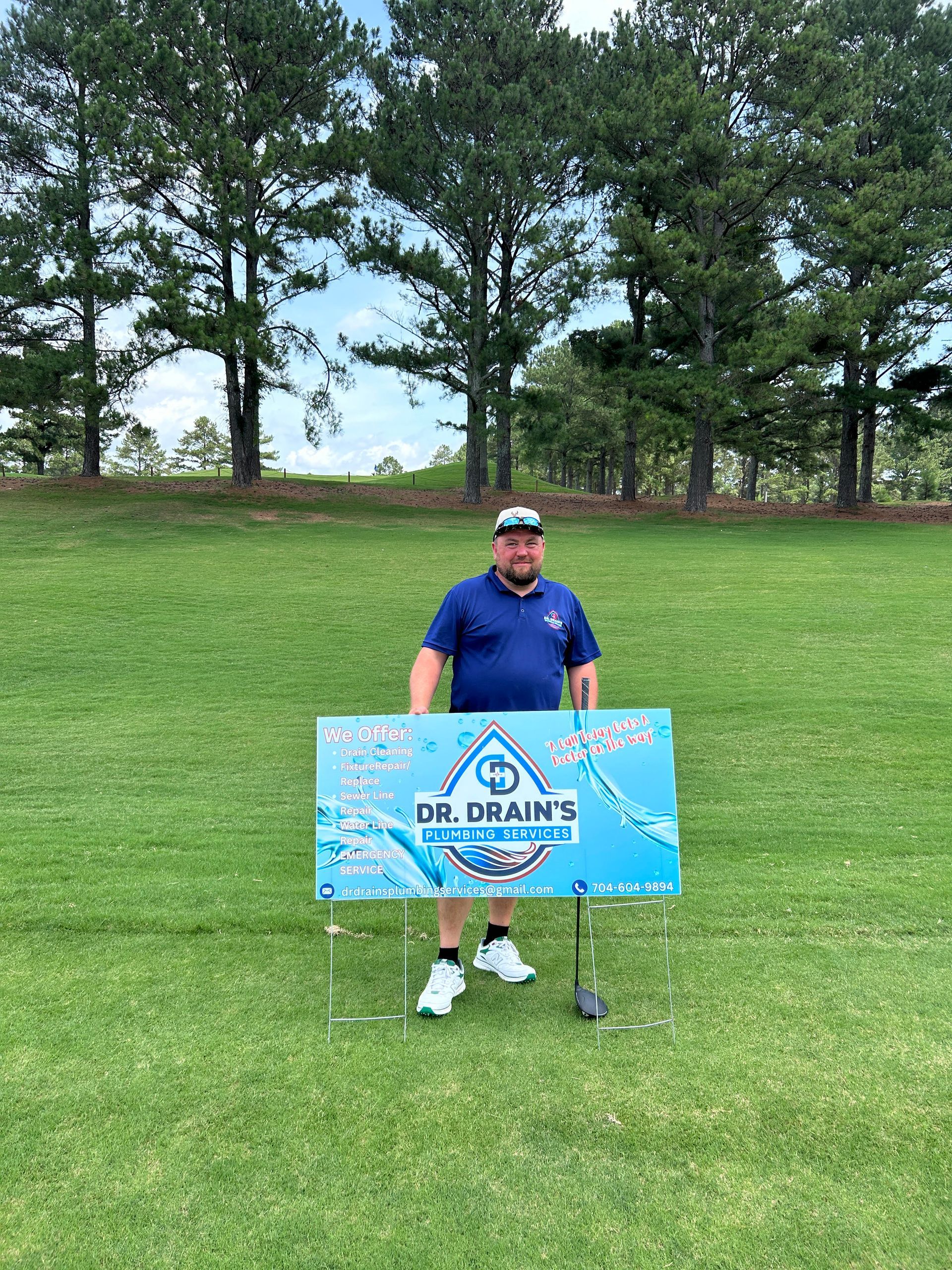 A man is standing on a golf course holding a sign.
