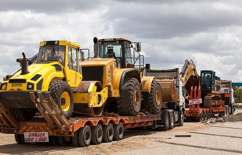 A large yellow tractor is sitting on top of a trailer.