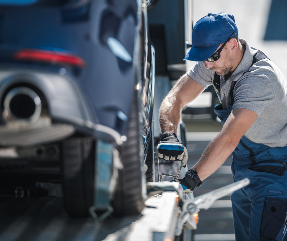 A man is working on a car on a tow truck.
