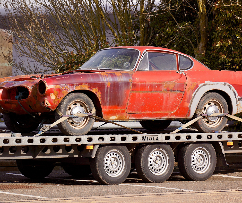 A red car is sitting on top of a tow truck.