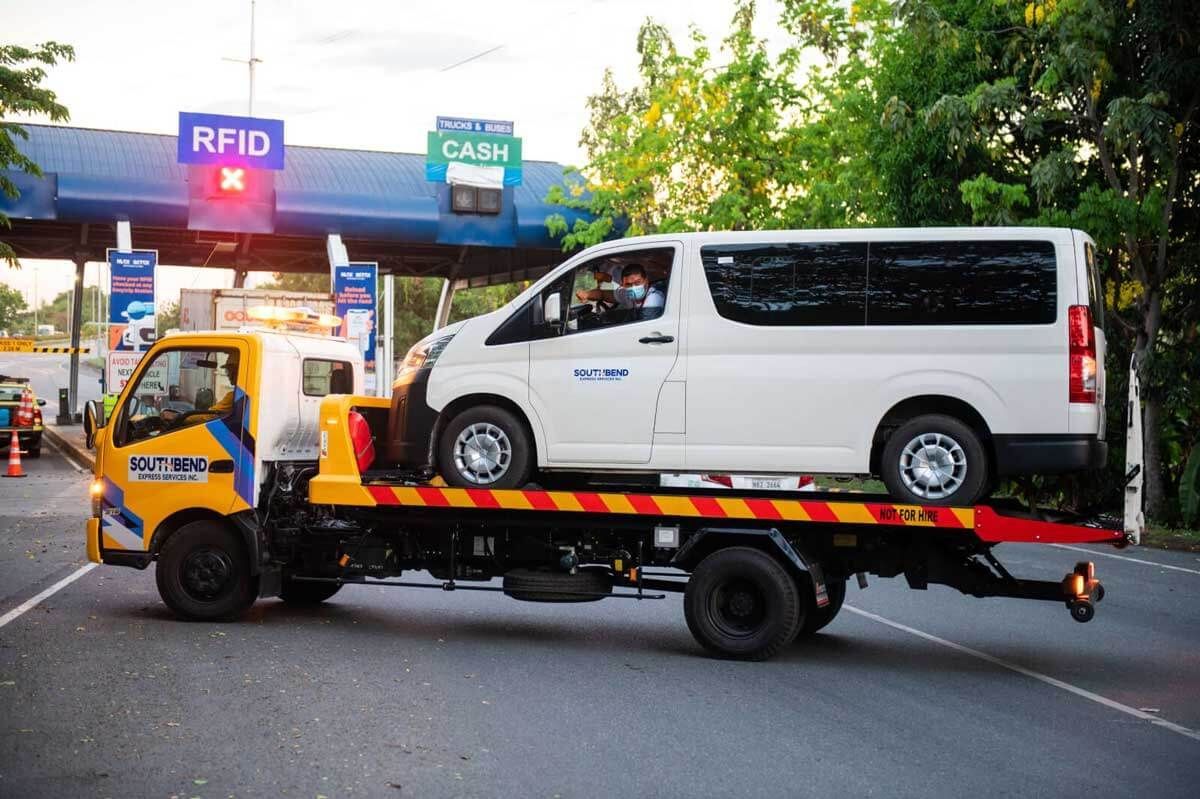 A white van is being towed by a tow truck.