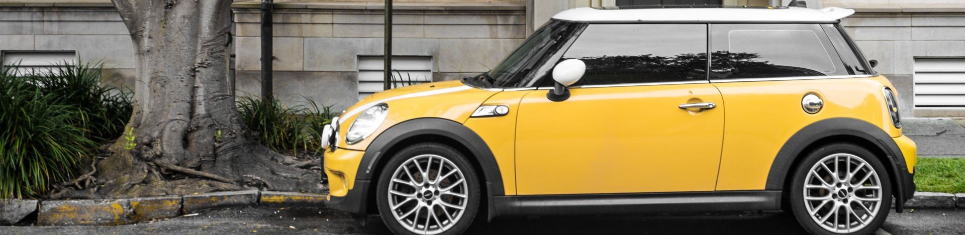 A yellow mini cooper is parked on the side of the road.