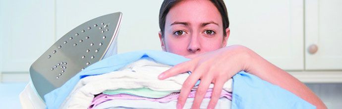 Woman looking over ironing pile and holding steam iron