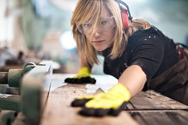 Female woodworker operating a workshop planer
