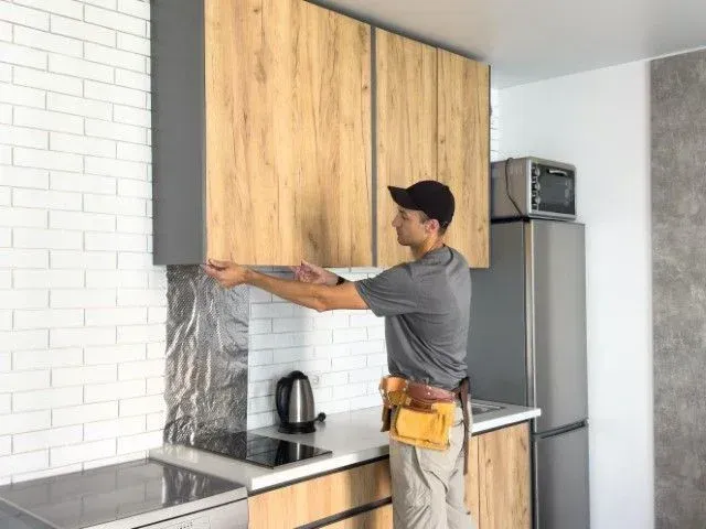 Carpenter installing modern wood upper cabinets