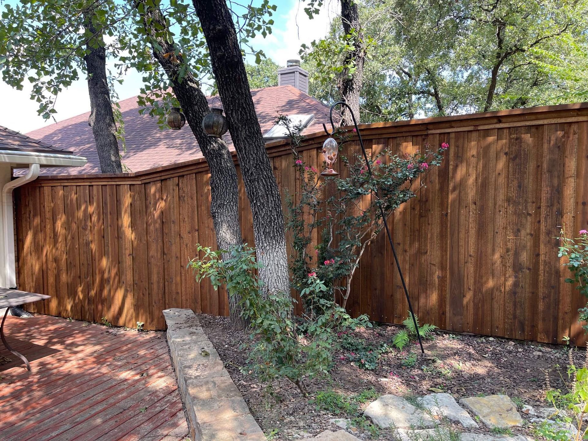 A Wooden Fence Is Surrounded by Trees in A Backyard