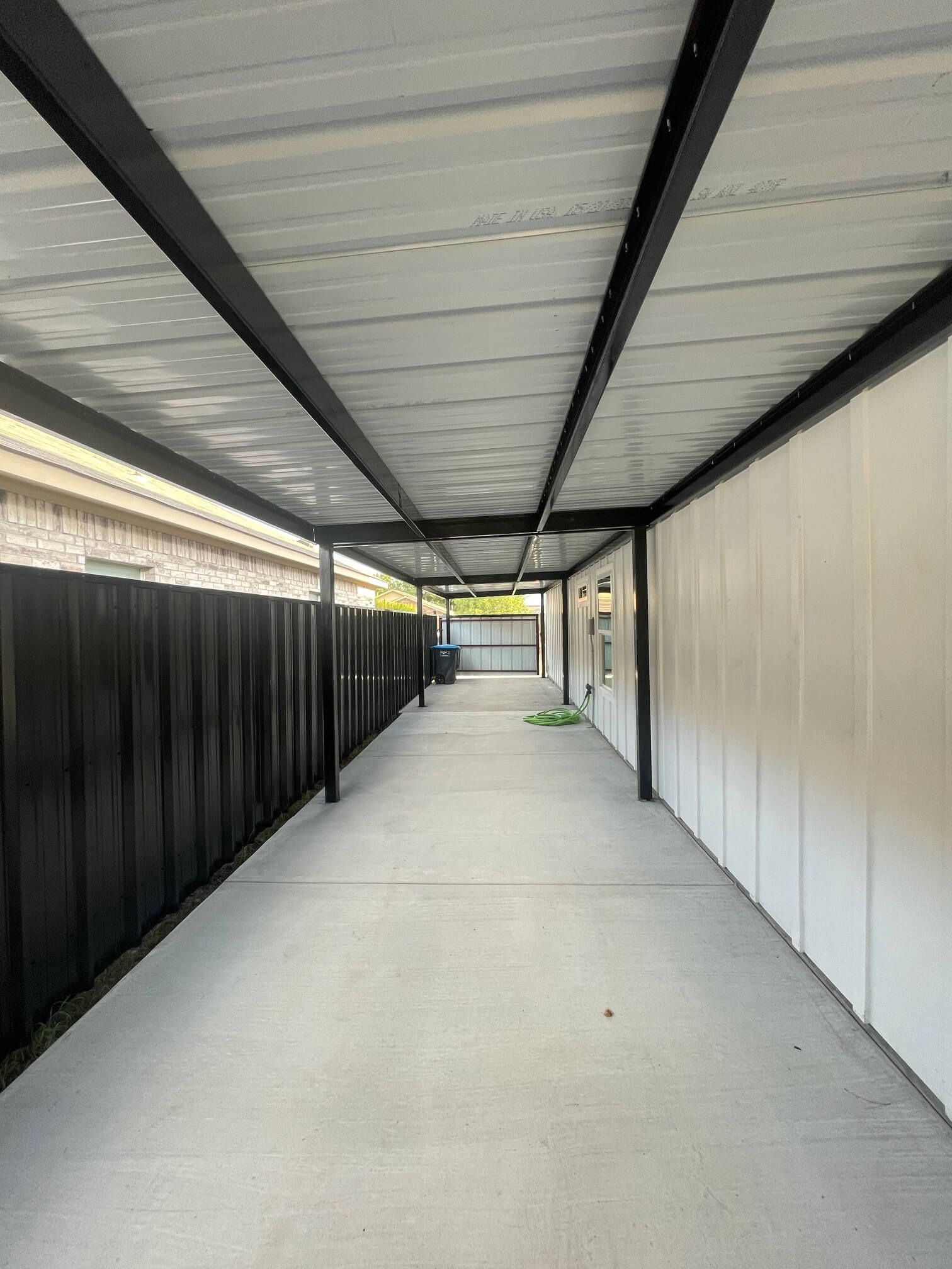 A Long Walkway Between Two Buildings with A Black Fence