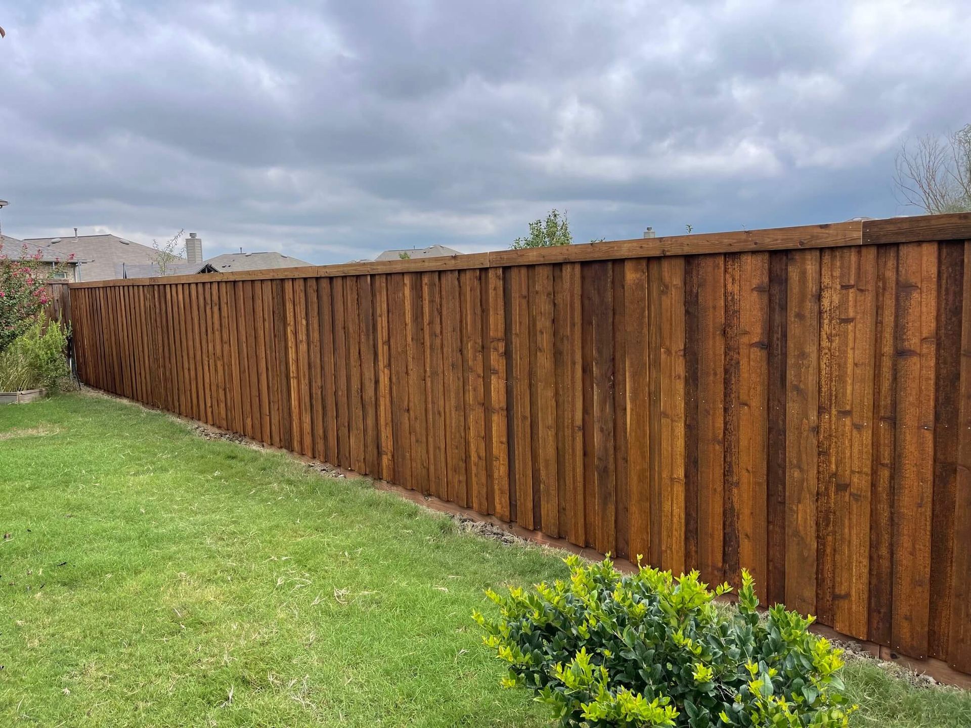 A Wooden Fence Surrounds a Lush Green Lawn in A Backyard