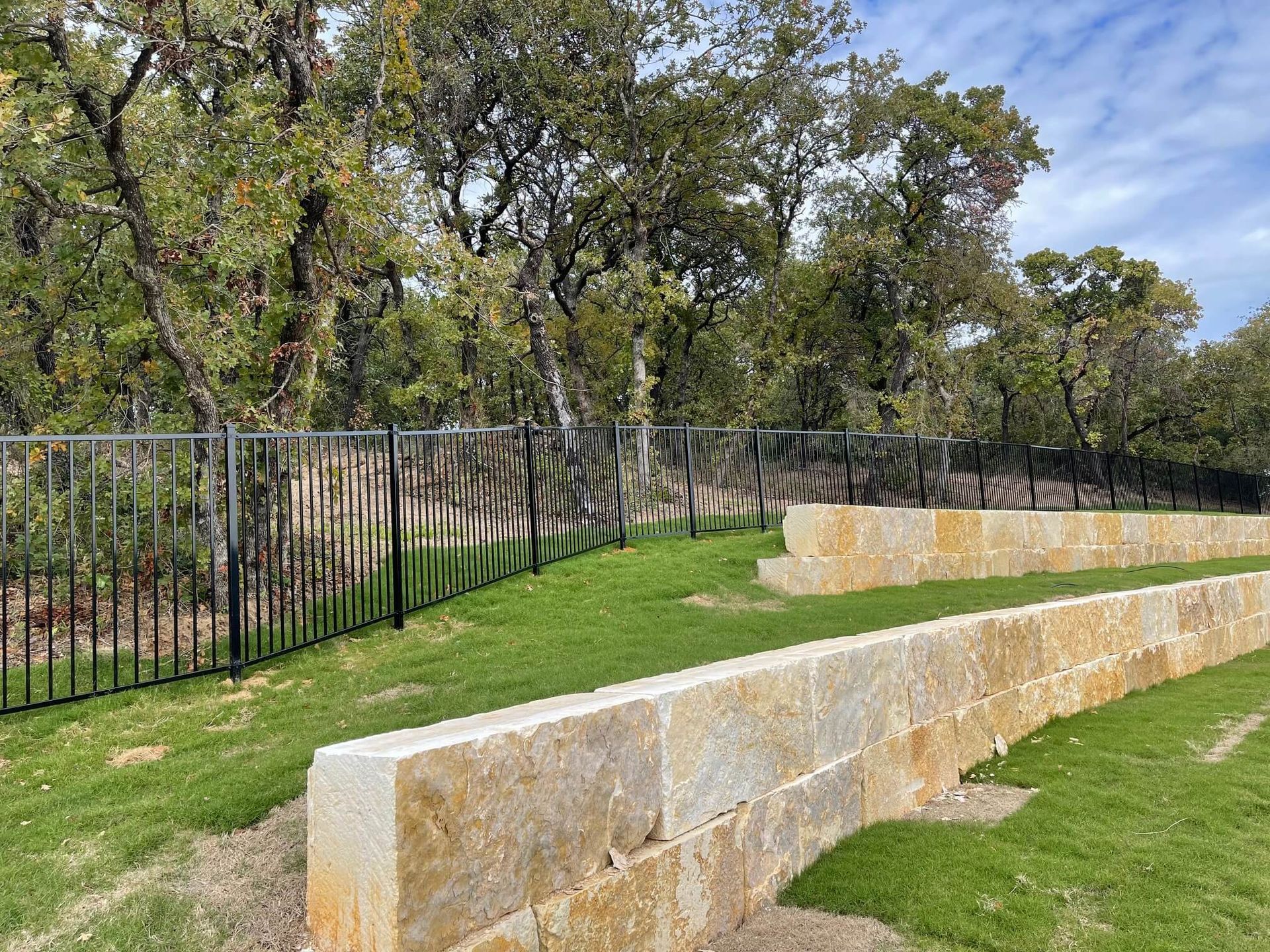 A Stone Wall Surrounded by A Metal Fence in A Park